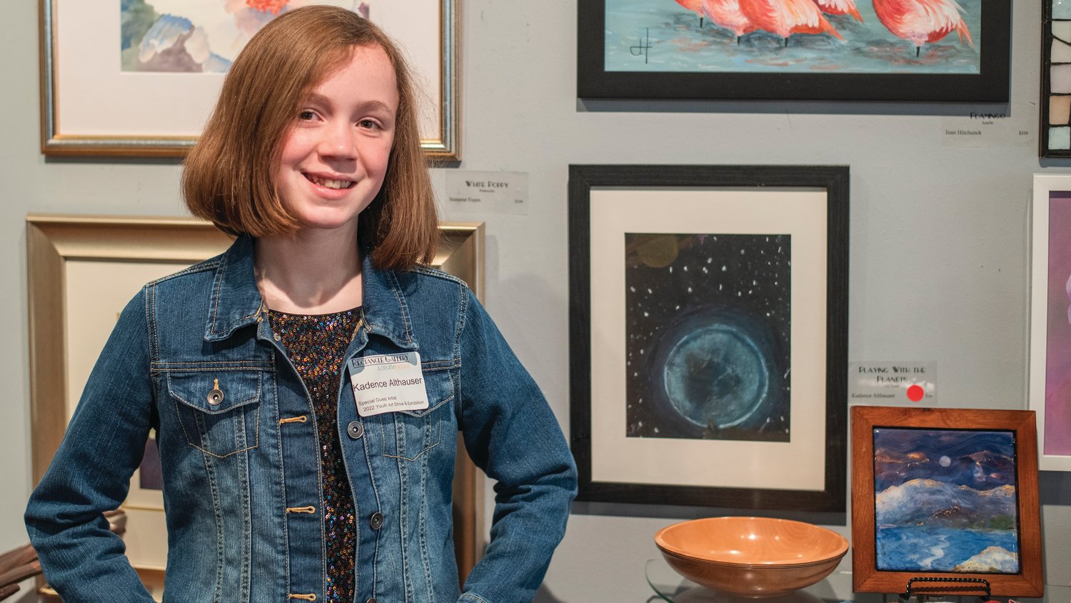 Kadence Althauser smiles and poses for a photo in front of her art titled, “Playing with the Planets,” at the Rectangle Gallery & Creative Space in Centralia.