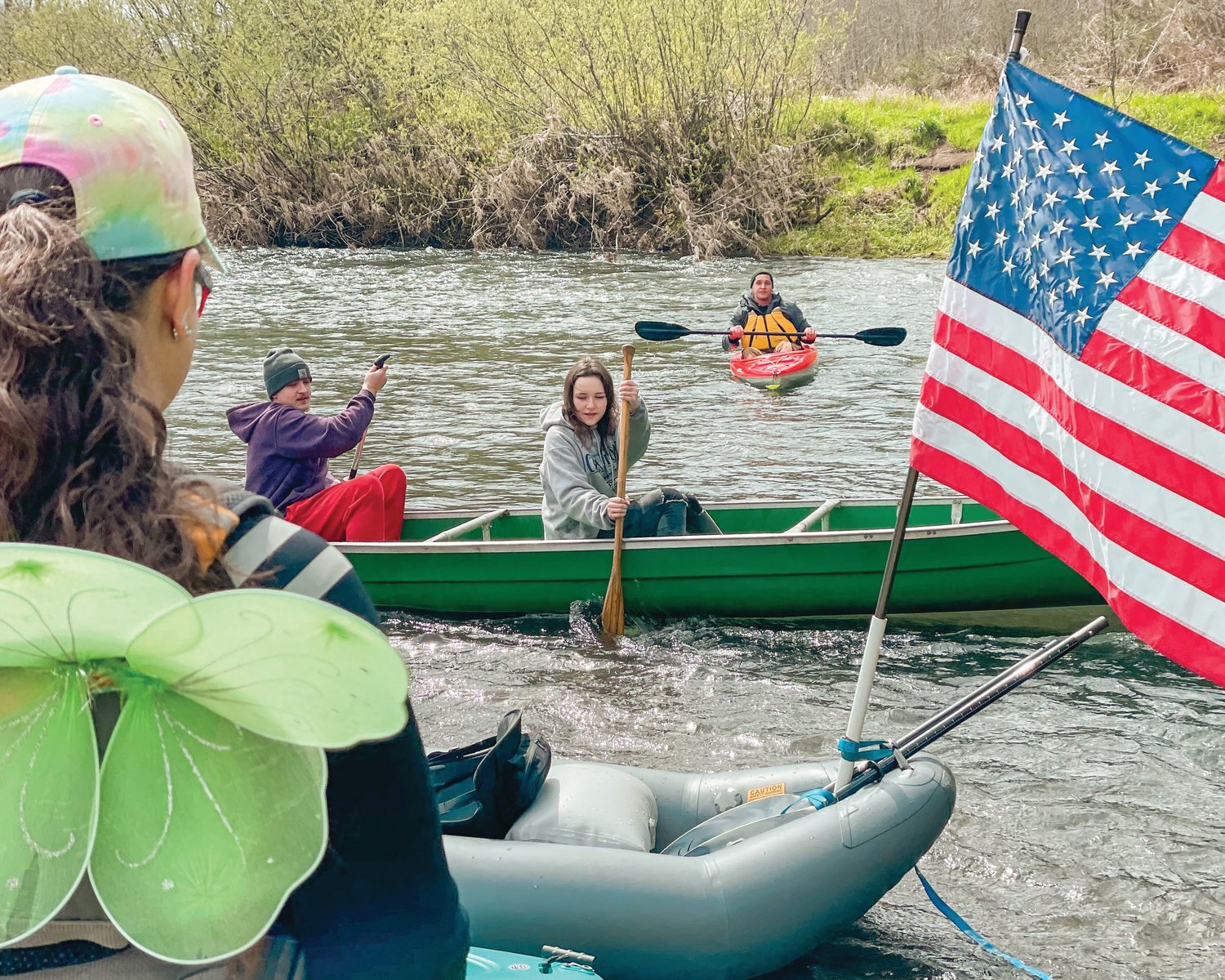 River runners sport hoodies, life vests, and fairy wings as flags wave from boats on shore of the Chehalis River on Saturday.