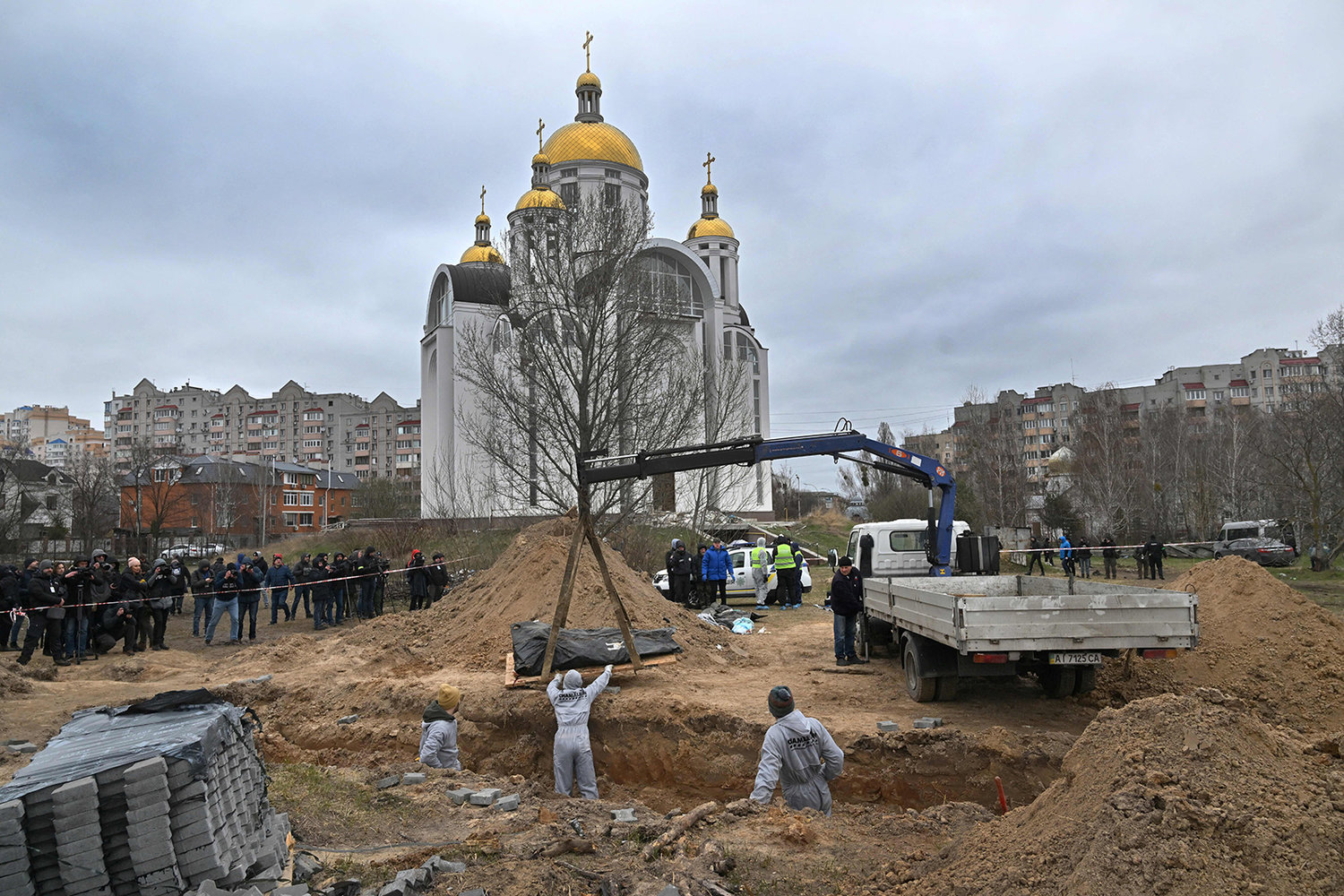 Journalists gather as bodies are exhumed from a mass-grave in the grounds of the St. Andrew and Pyervozvannoho All Saints church in the Ukrainian town of Bucha, northwest of Kyiv, on April 13, 2022. The European Commission President visited the mass grave in Bucha on April 8, where Russian forces are accused by Ukraine's allies of carrying out atrocities against civilians. (Sergei Supinsky/AFP via Getty Images/TNS)