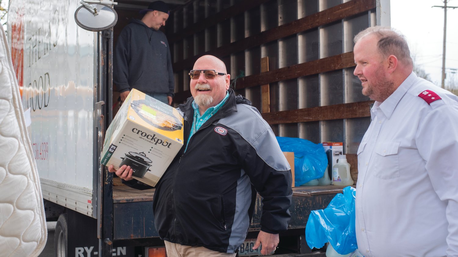 Lewis County Emergency Management Deputy Director Ross McDowell smiles while carrying a crockpot alongside a mattress and other items with Steven Pack of the Salvation Army for residents moving back into the Chehalis Avenue Apartments on Wednesday afternoon.