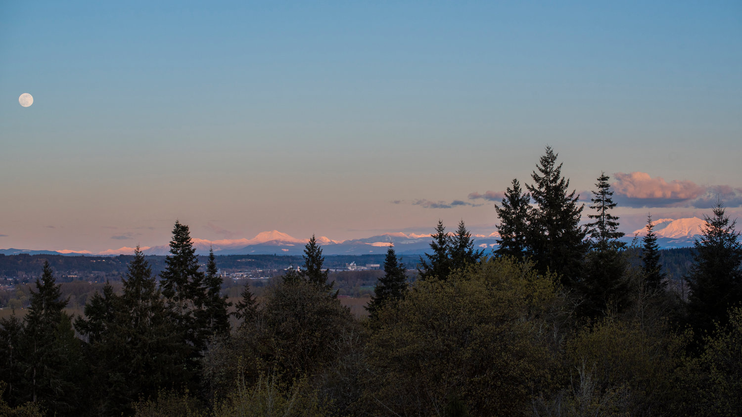 The moon, Mount Adams and Mount St. Helens glow at sunset.