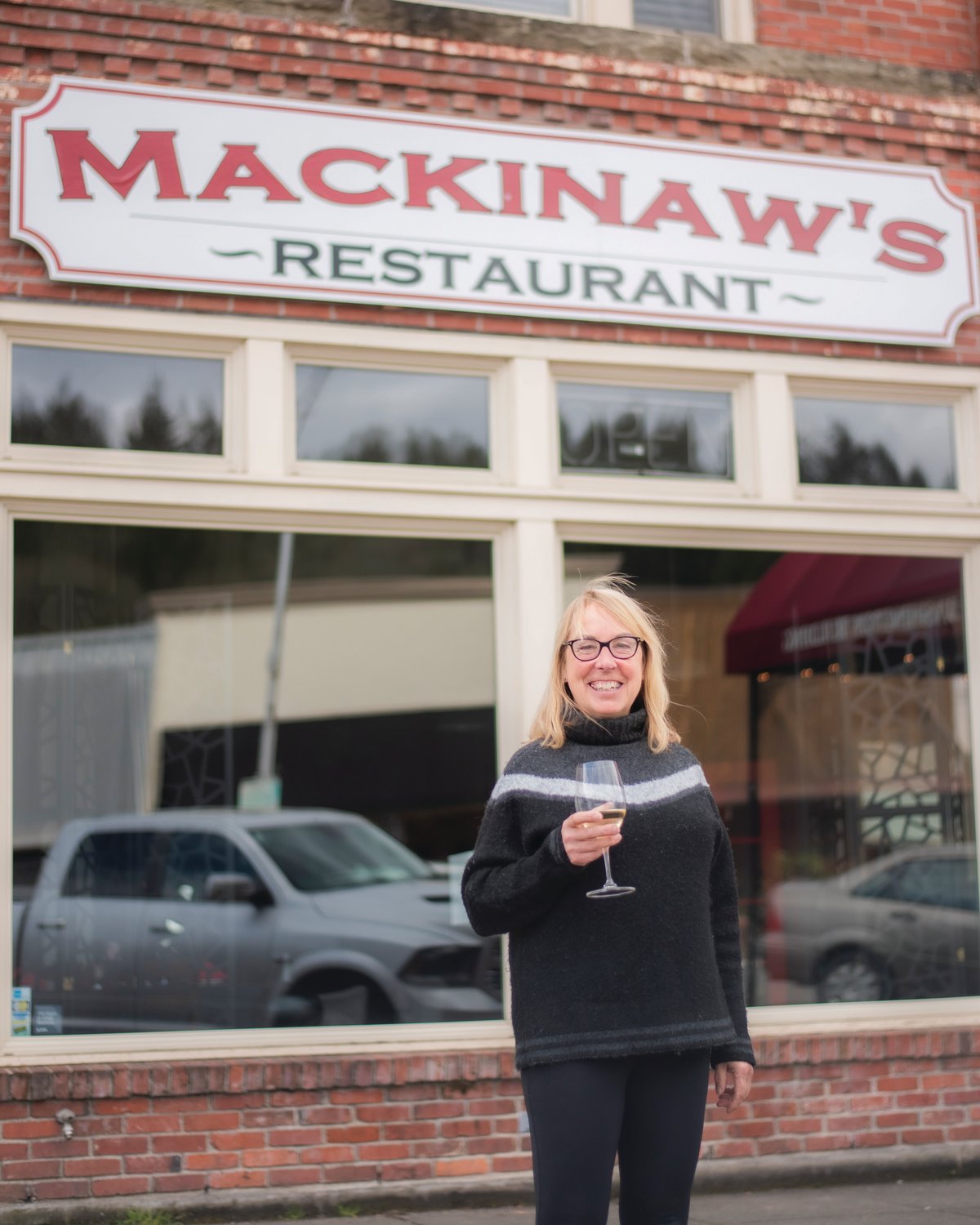 Jared Wenzelburger / jared@chronline.com
Laurel Khan smiles outside Mackinaw’s while holding a glass of non-alcoholic  wine Tuesday afternoon.