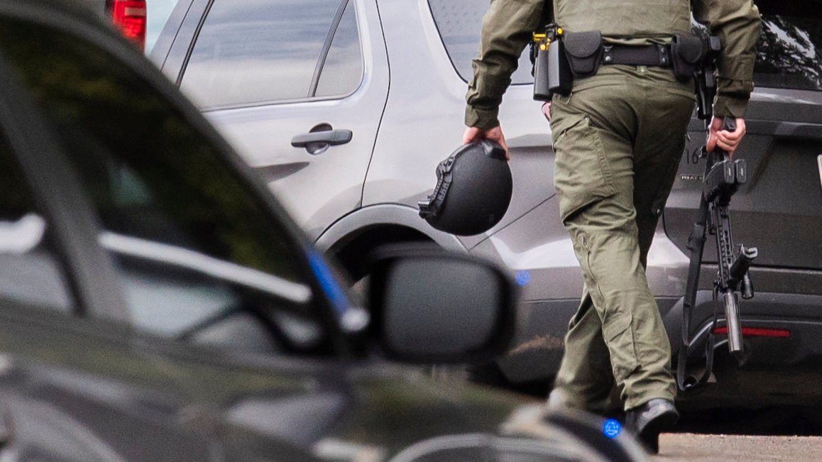 Weapons and helmets are carried through a scene in the 100 block of Carroll Way off Frogner Road Thursday in Chehalis.