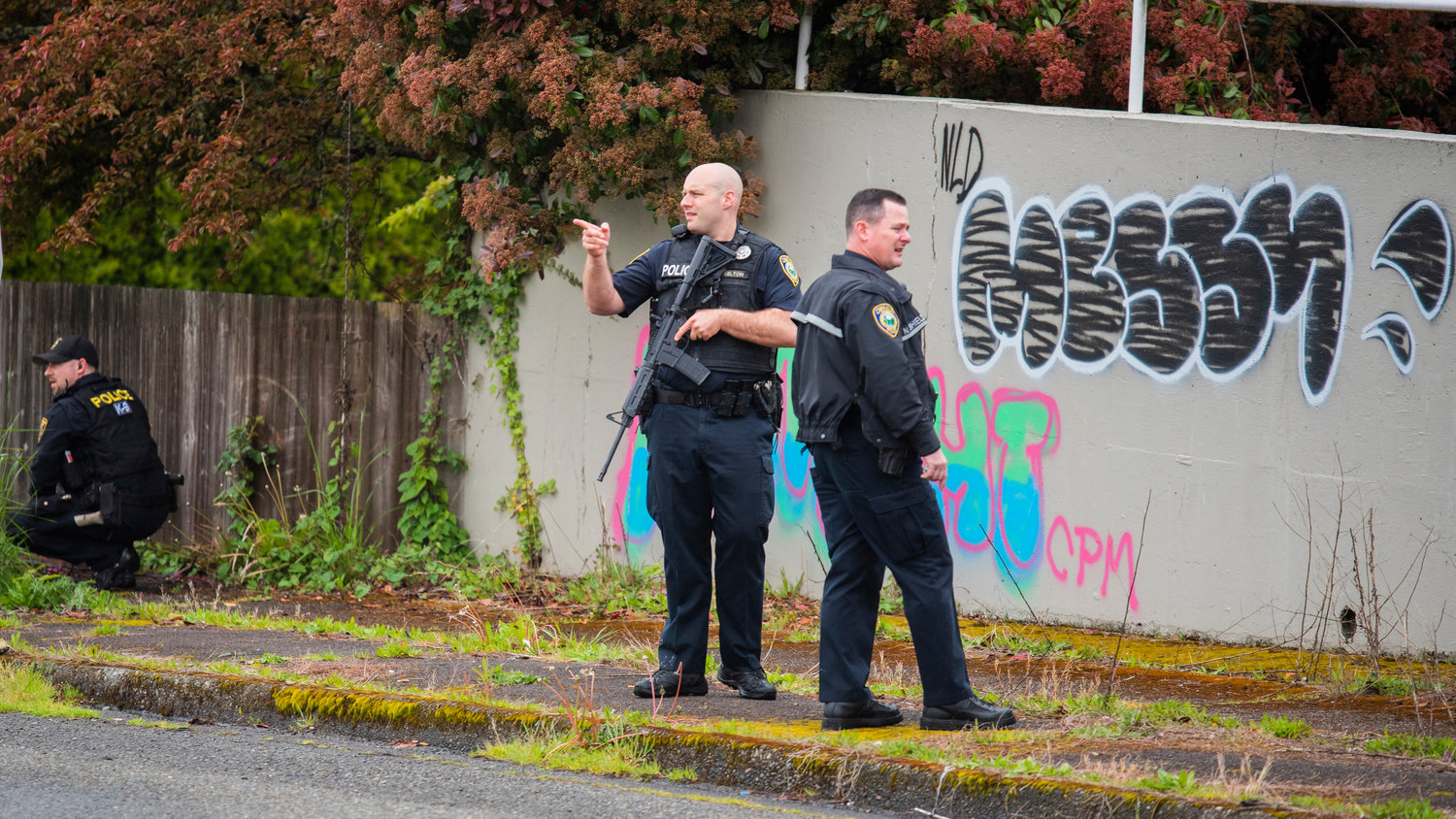 Police officers look on with weapons indexed and dogs searching outside of Chase Bank in Chehalis on Friday.