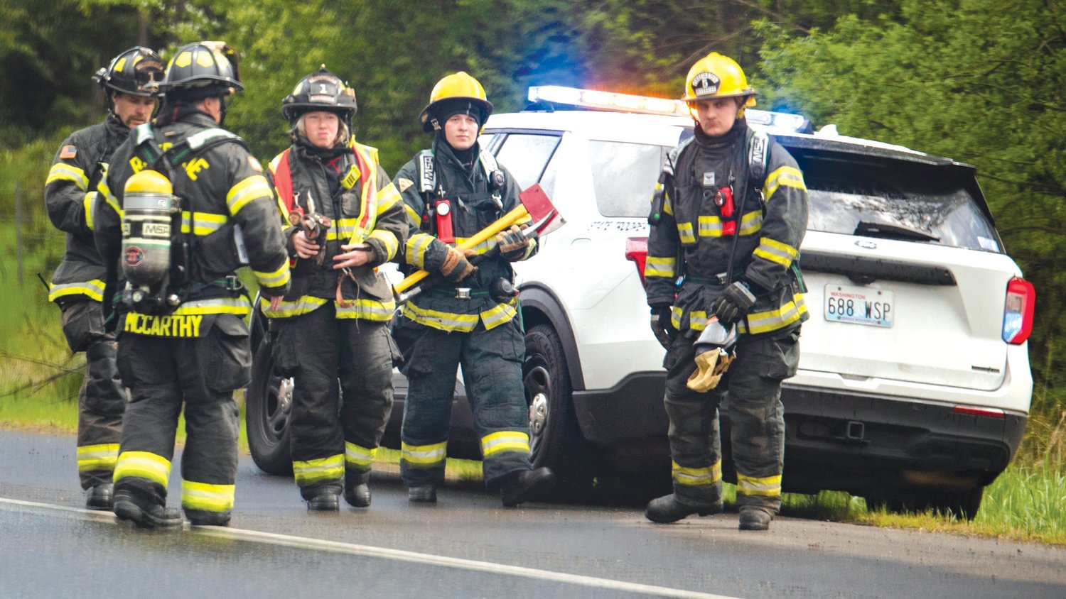Firefighters from Riverside Fire Authority carry axes and other equipment down the shoulder of Interstate 5 southbound near milepost 86 Tuesday afternoon following a car fire in Grand Mound.
