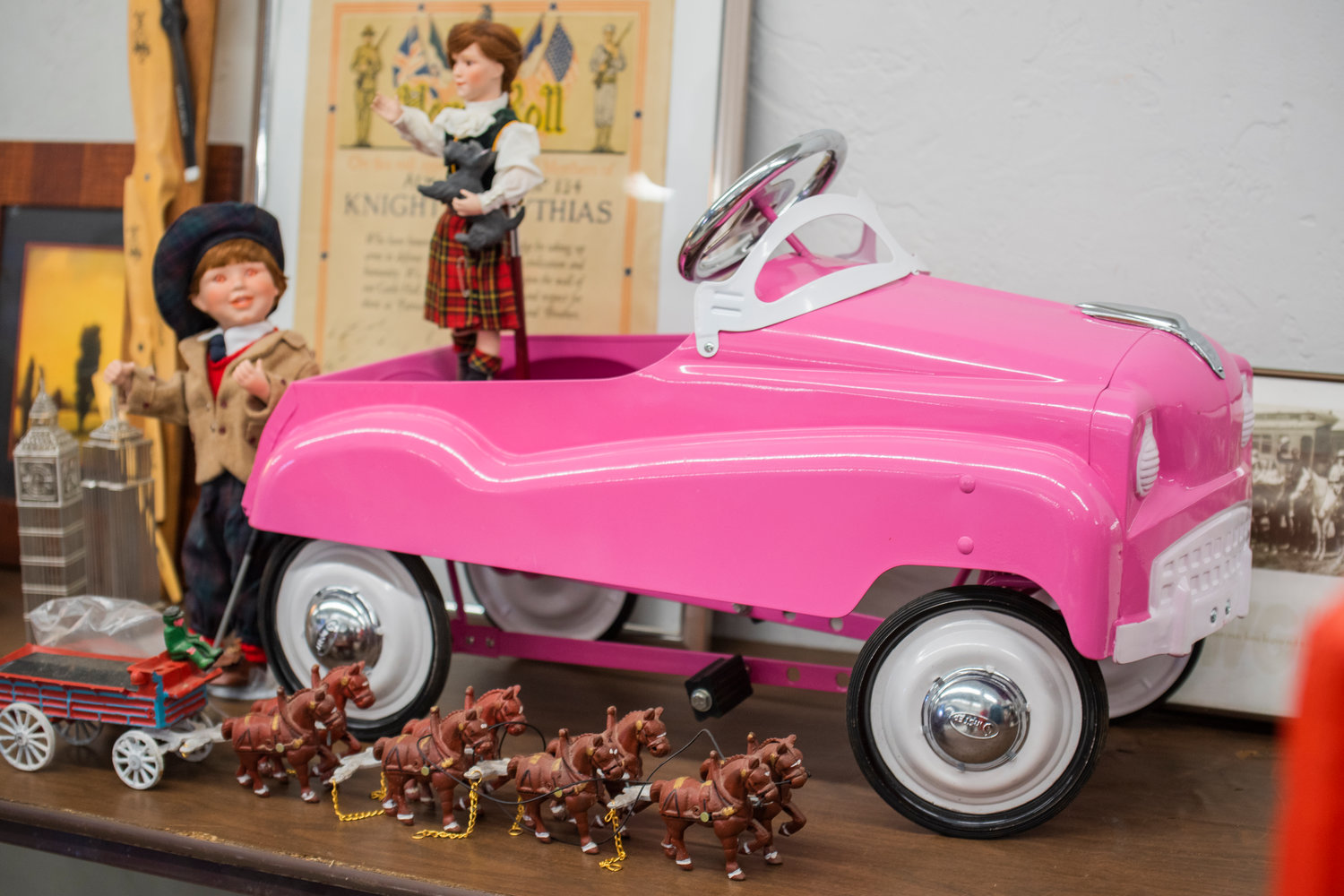 A pink pedal car sits on a table near antique figurines during the Spring Community Garage Sale on Saturday.