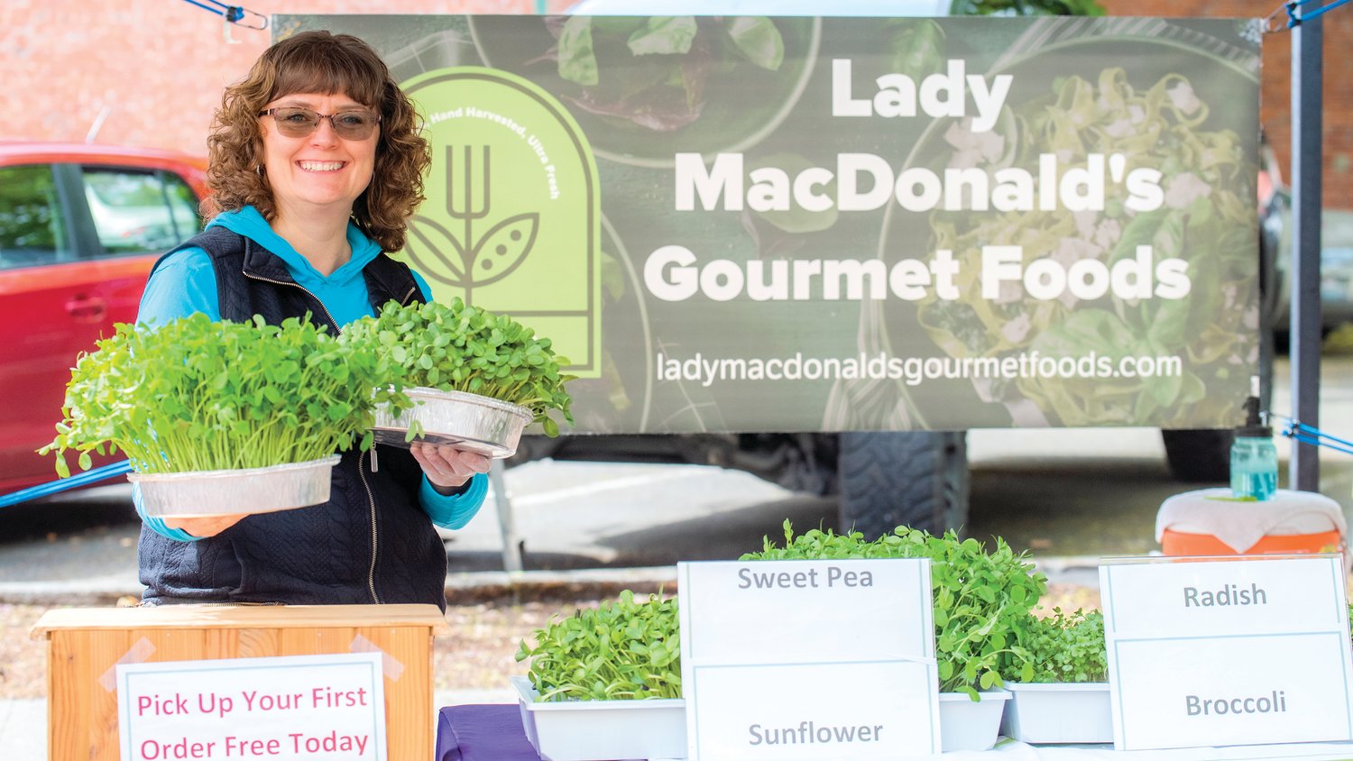 Heidi MacDonald, with Lady MacDonald’s Gourmet Foods, smiles while holding up microgreens at Pine Street Plaza during her Centralia Farmers Market debut Friday morning.