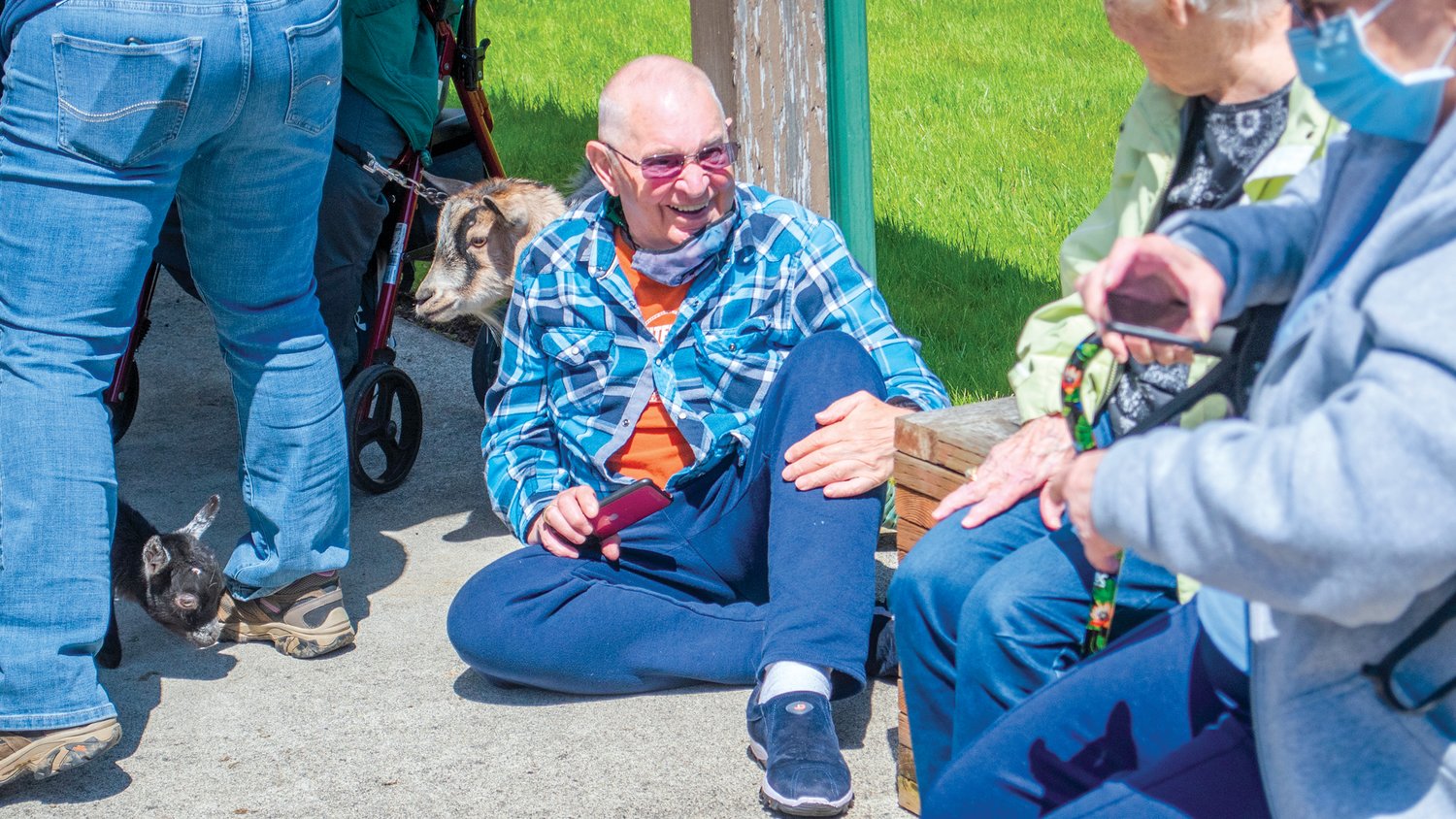Jerry Blanchard smiles while sitting on the ground next to pygmy goats at Woodland Village Concepts of Chehalis Thursday afternoon.