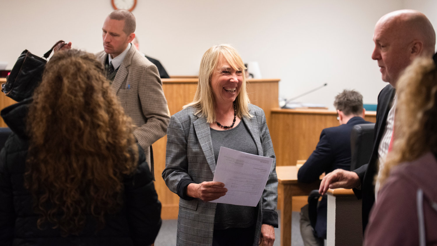 Laurel Khan, owner of Mackinaw's Restaurant and connected bar, Curious, in Chehalis, smiles as she is greeted following an appearance in Lewis County District Court Tuesday morning.