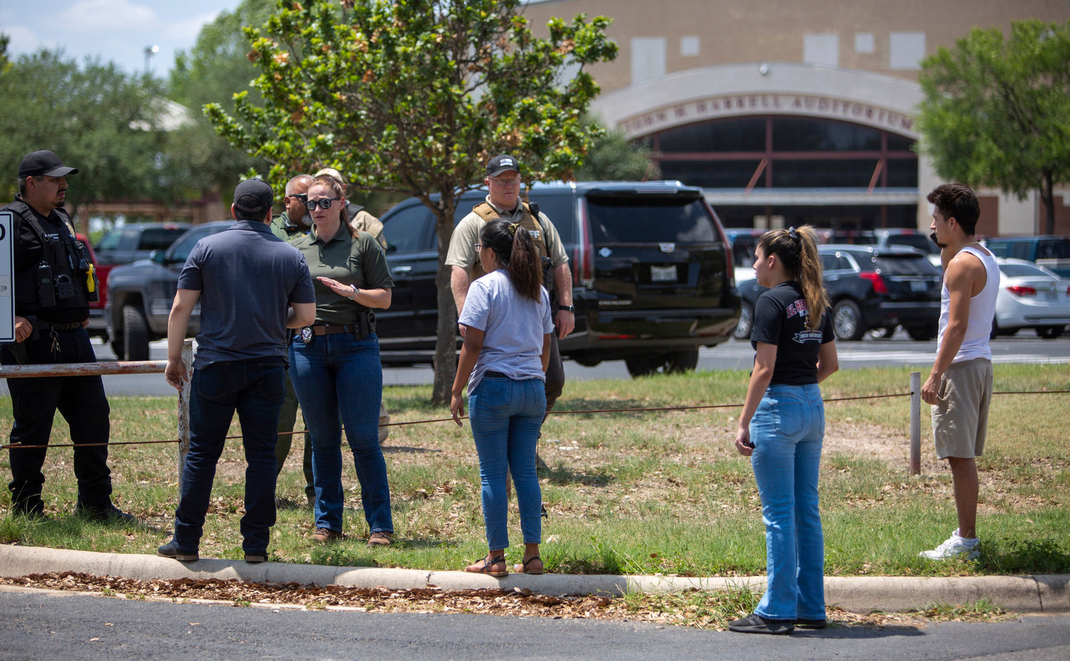 A law enforcement officer tells people Tuesday afternoon, May 24, 2022, that Uvalde High School is secure after a school shooting at the nearby Robb Elementary School in Uvalde, Texas. (William Luther/San Antonio Express-News/Zuma Press/TNS)
