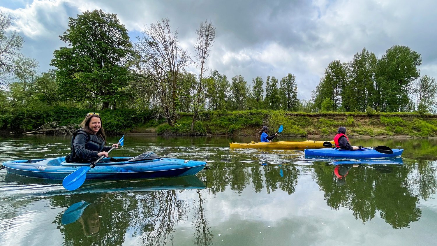 From left, Justyna Tomtas, Jordan Nailon, and Isabel Vander Stoep paddle through Centralia in kayaks on the Chehalis River Wednesday morning.