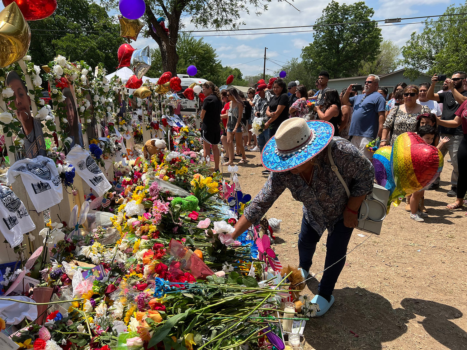 Visitors lay flowers at a memorial outside Robb Elementary School in Uvalde, Texas, where 19 children and two teachers were killed in a mass shooting. (Molly Hennessy-Fiske/Los Angeles Times/TNS)