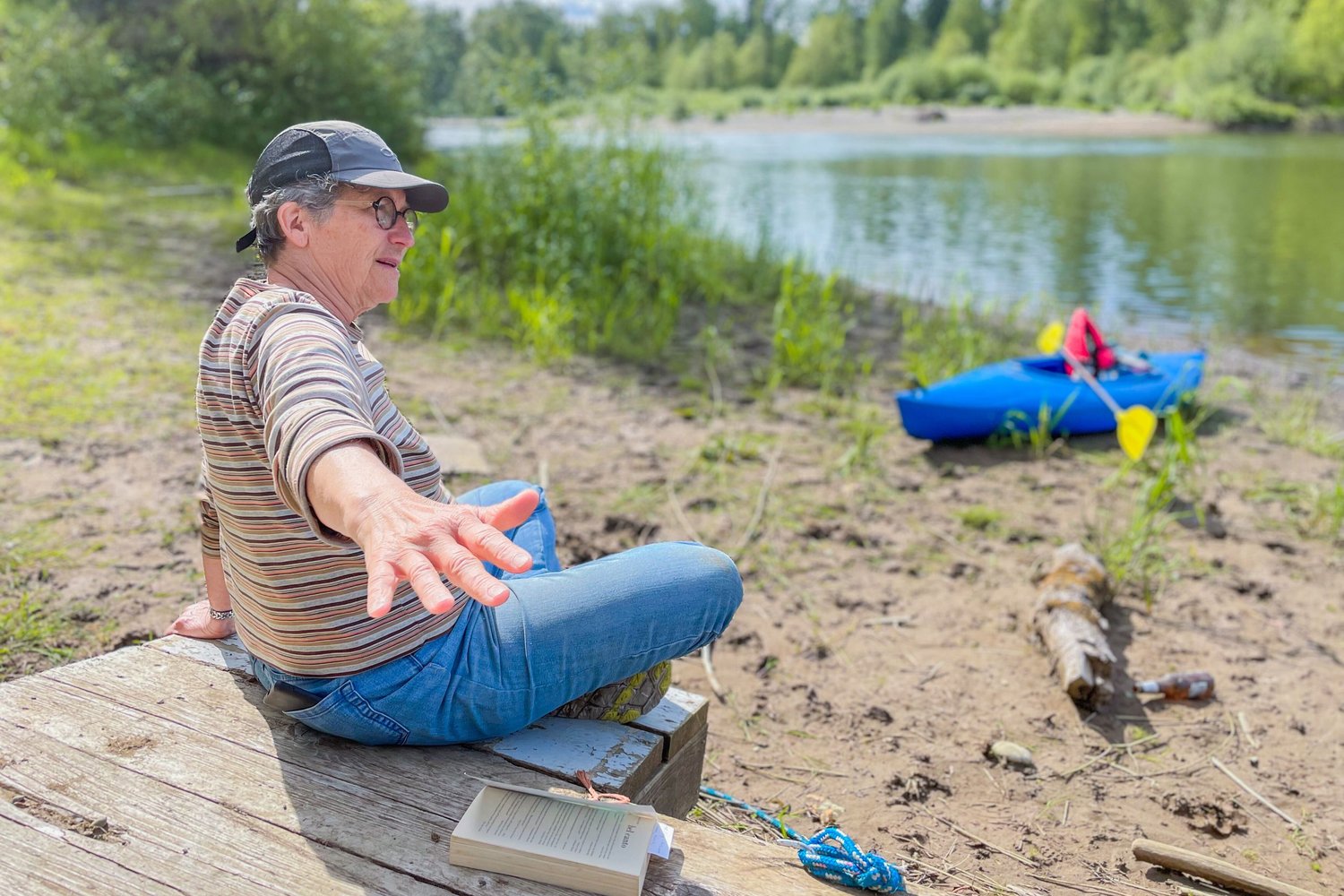 A paperback of Bel Canto sits on a dock next to Betsie De Wreede, a retired farmer in the Independence Valley, as she talks about flooding along the Chehalis River.