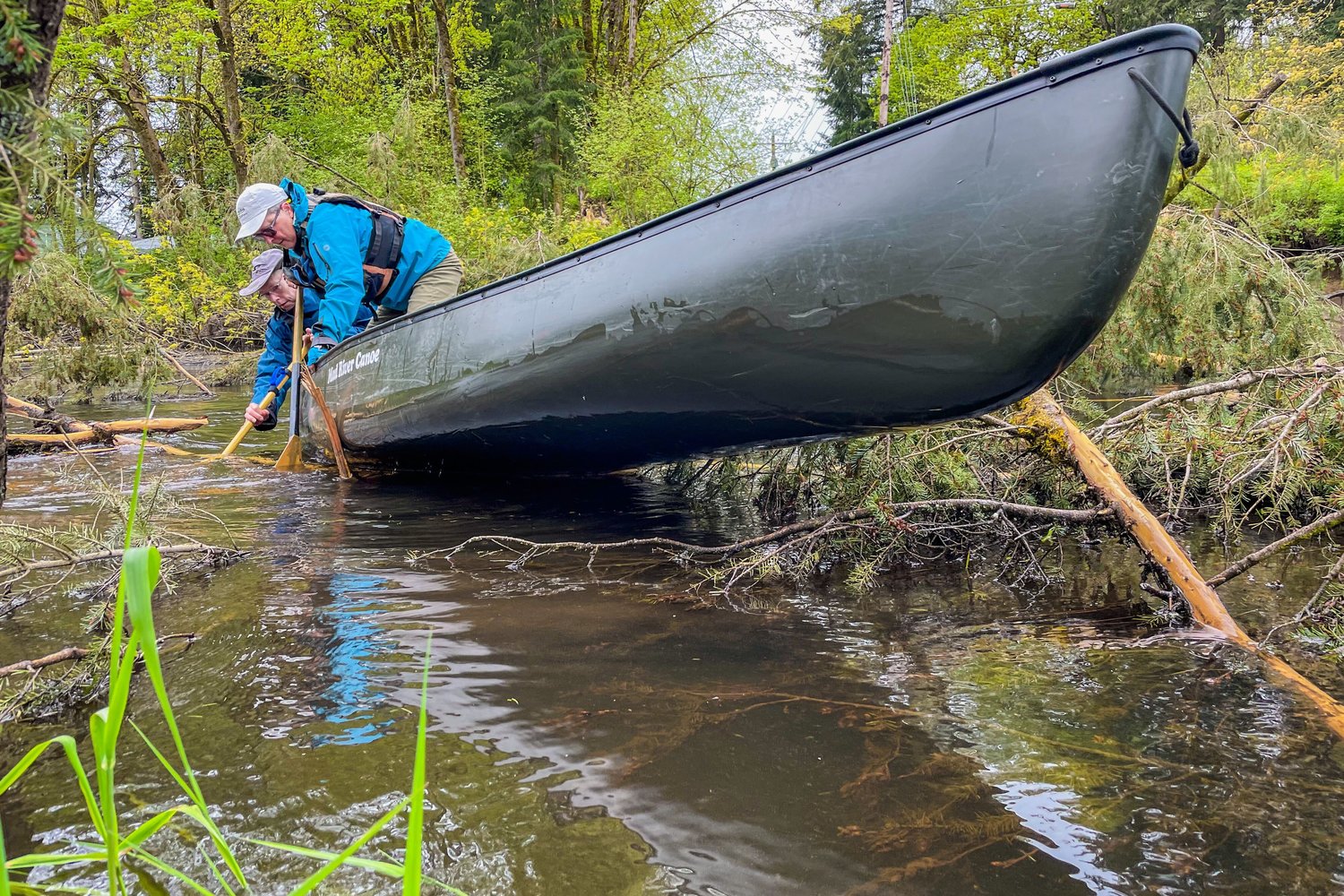 Geomorphologist Paul Bakke and Lee First, an environmental activist, work to maneuver their canoe through a downed tree along the Black River.
