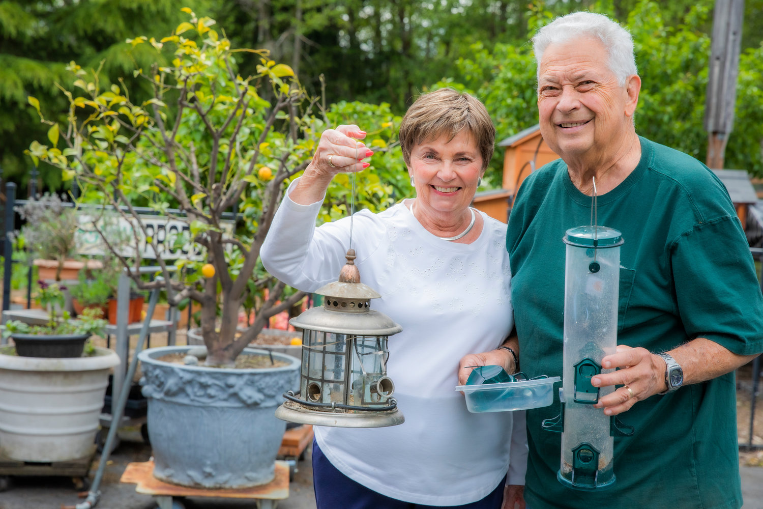 Margie and Russ Trentlage smile while holding up bird feeders they have worked to fix after a bear sunk teeth and claws into feeders for the food inside.