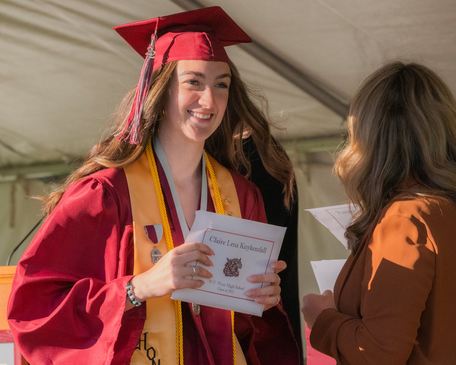 Claire Kuykendall smiles and holds up her W.F. West High School Class of 2022 diploma at Bearcat Stadium Saturday in Chehalis.