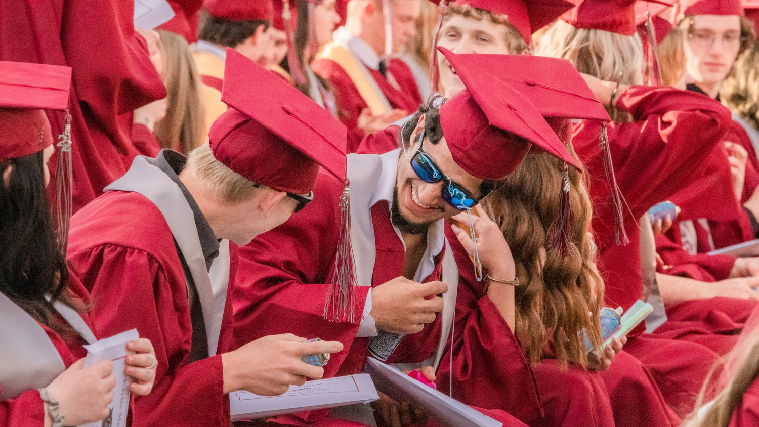 Silly String clings to sunglasses as graduates laugh before turning the tassels at Bearcat Stadium Saturday in Chehalis.