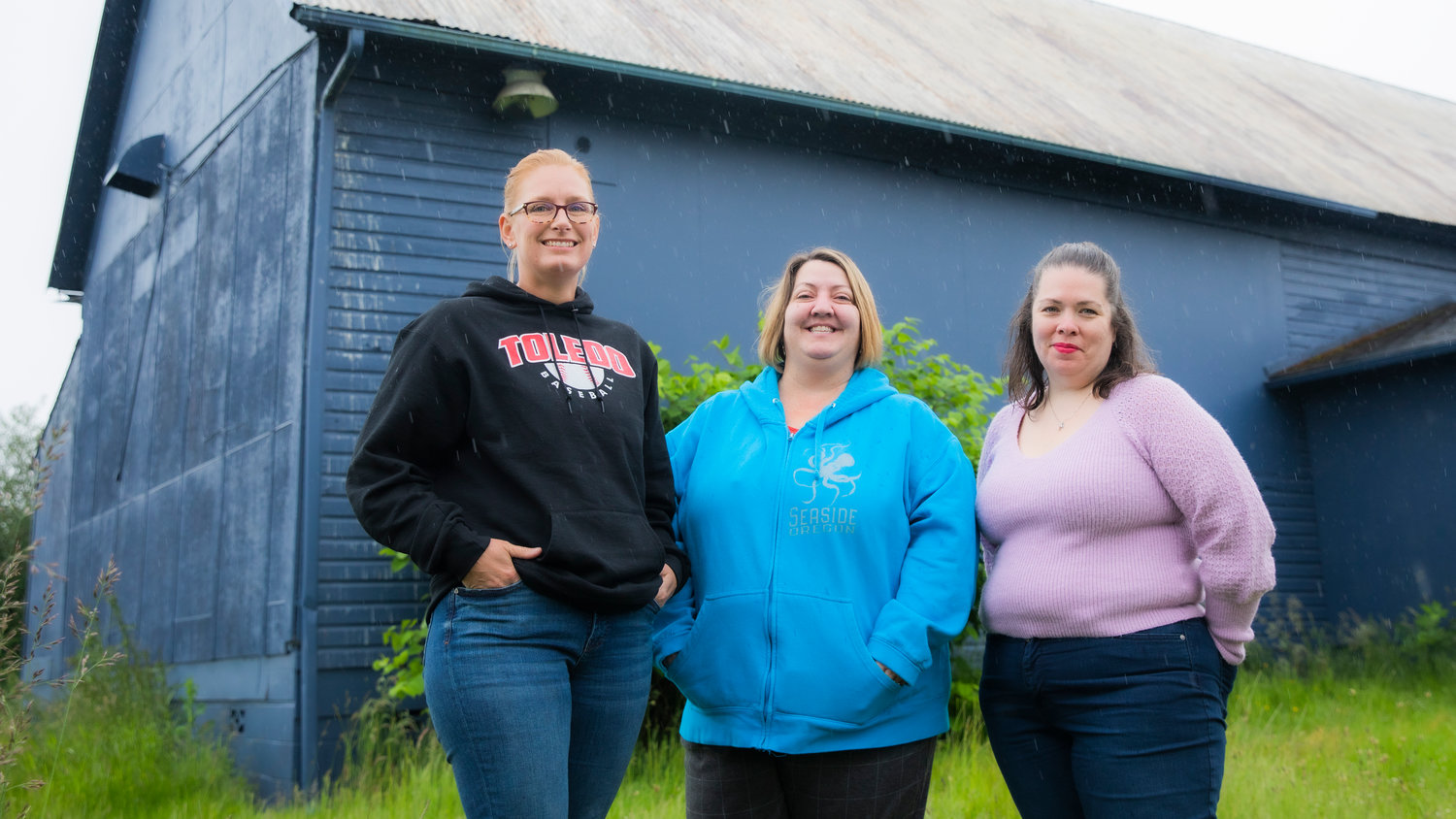 From left to right, Toledo Neighbors Vice President Brooke Acosta, President Amber Buck and Co-Treasurer Heather Garman pose for a photo outside in Toledo as it rains.