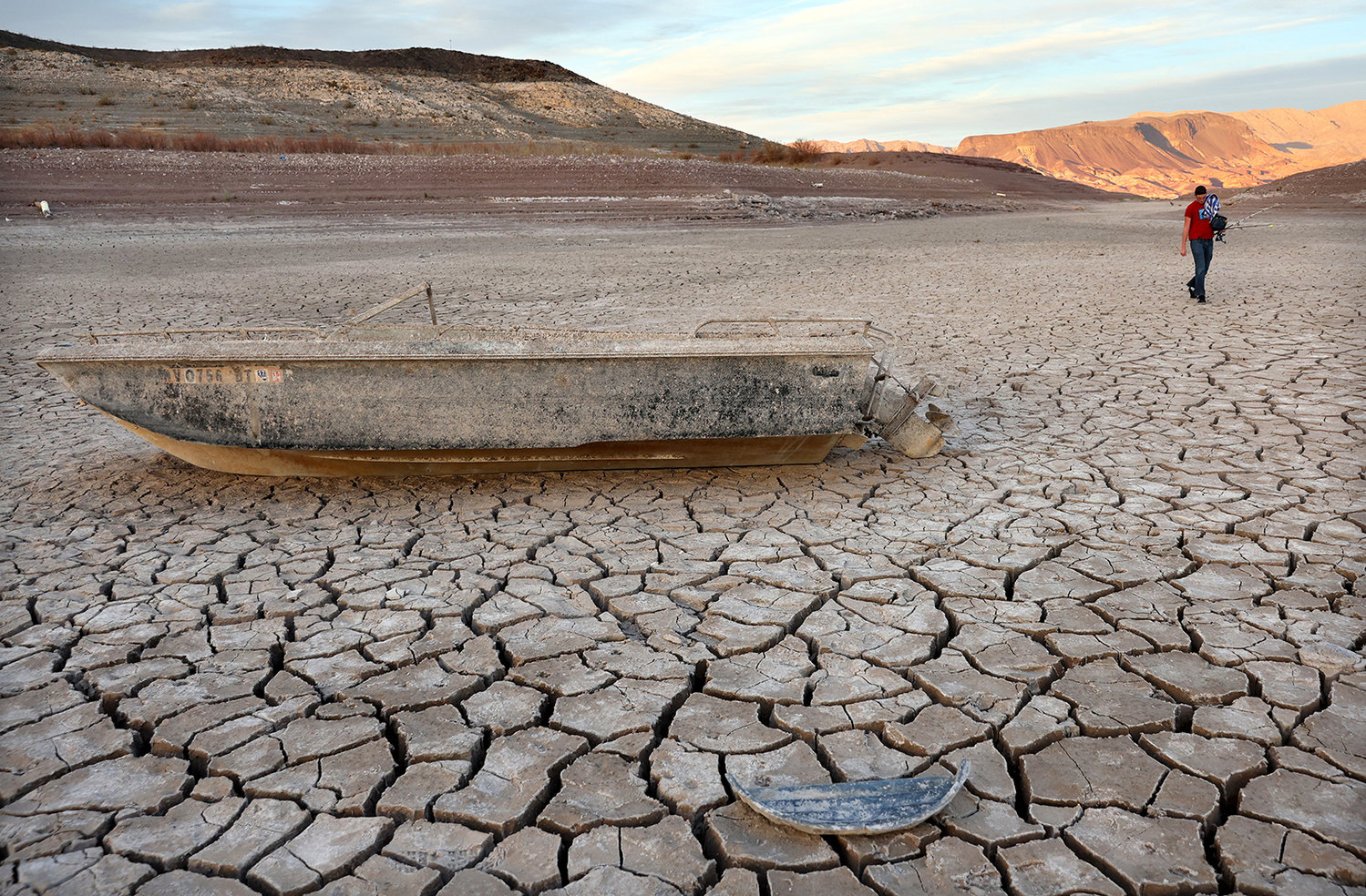 A person who was fishing nearby walks past a formerly sunken boat resting on a now-dry section of lakebed at the drought-stricken Lake Mead on May 10, 2022, in the Lake Mead National Recreation Area, Nevada. The U.S. Bureau of Reclamation reported that Lake Mead, North America's largest artificial reservoir, has dropped to about 1,052 feet above sea level, the lowest it's been since being filled in 1937 after the construction of the Hoover Dam. (Mario Tama/Getty Images/TNS)