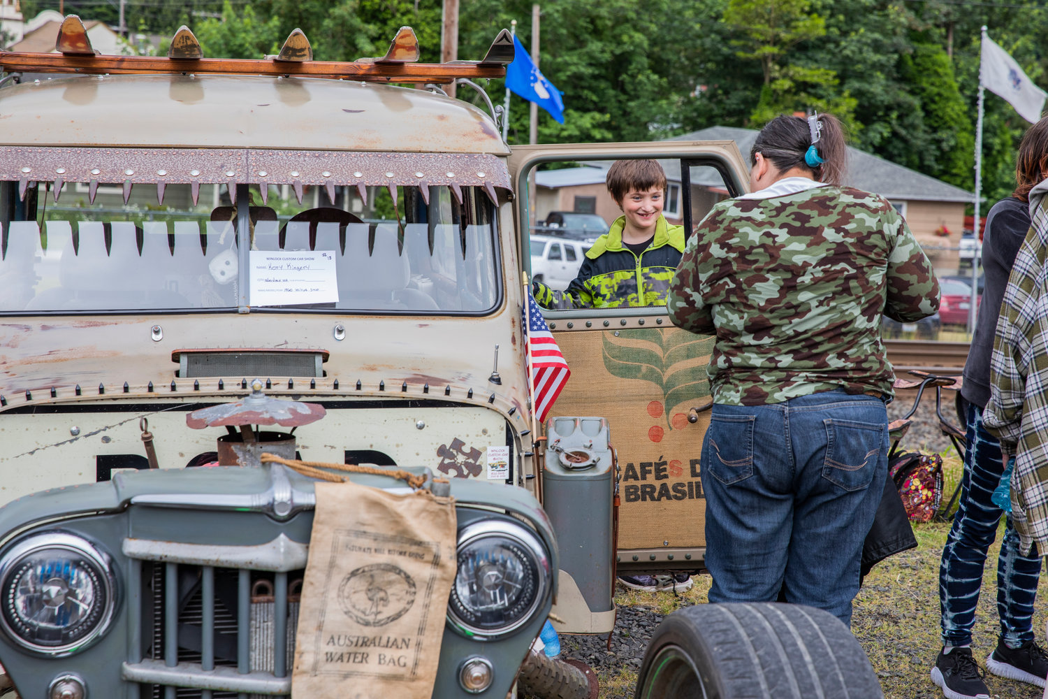 Kids smile next to vehicles on display during the Winlock Custom Car Show on Saturday.