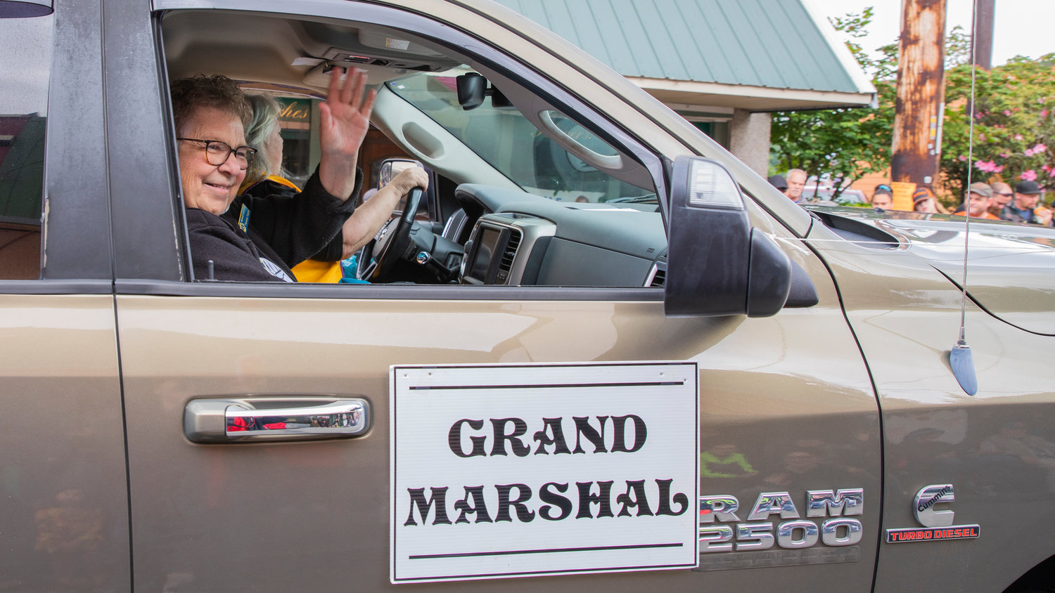 The Egg Days Festival Grand Marshal smiles and waves from a truck during a Saturday parade in Winlock.