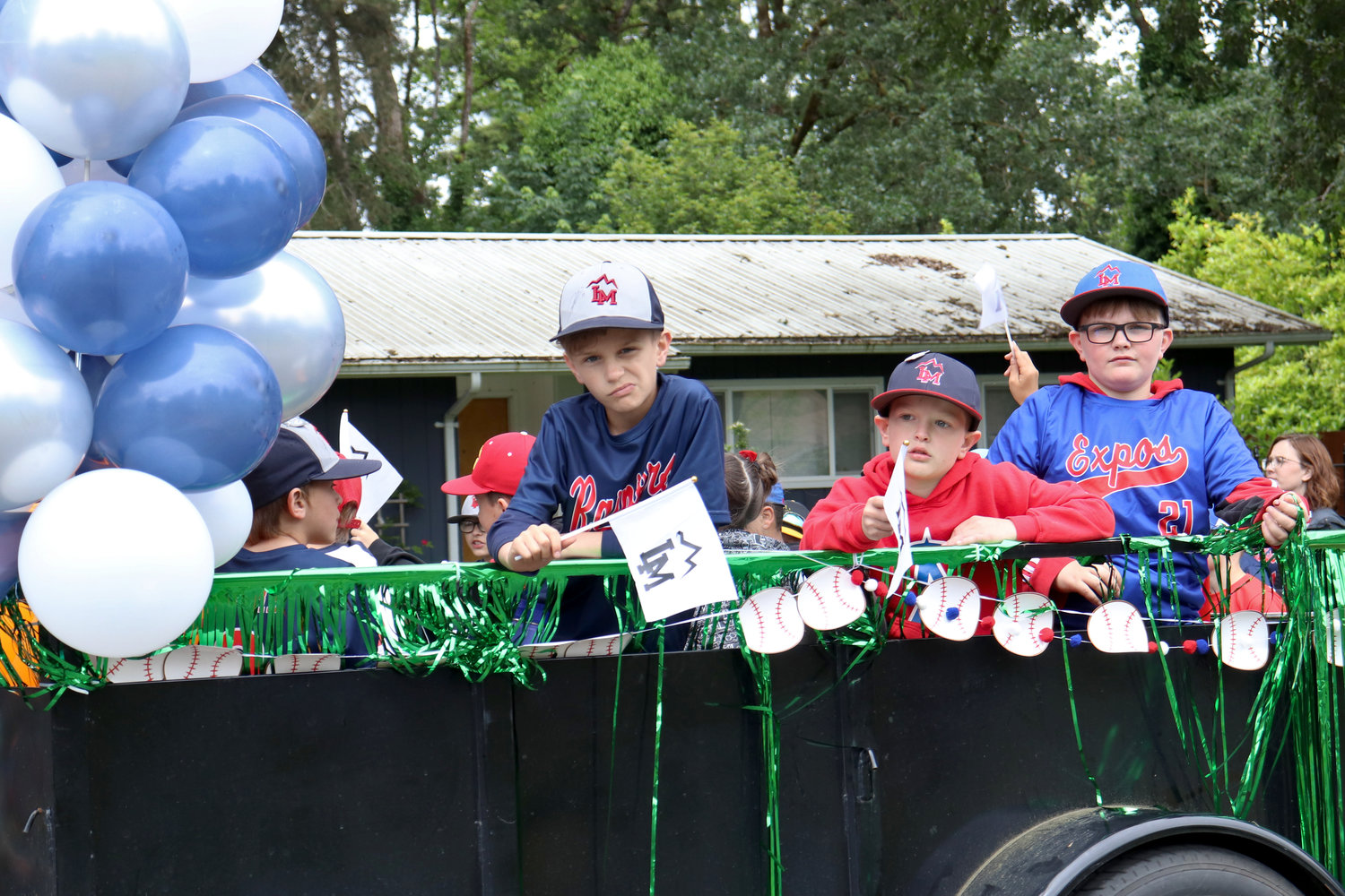Members of the Larch Mountain Little League wave flags from a float during the Swede Day Parade in Rochester on Saturday.