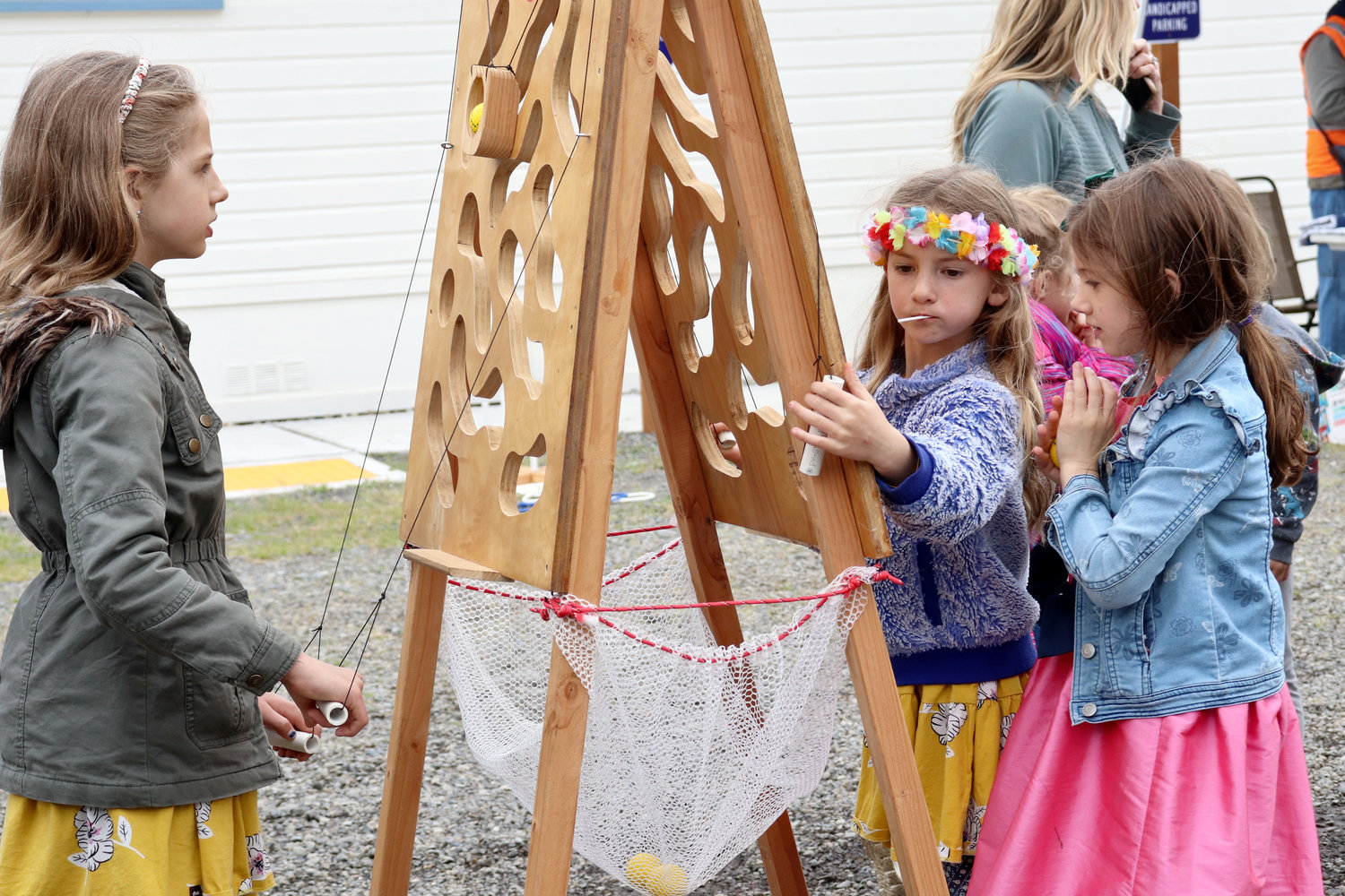 From left, Junia, Linnea and Abigail attempt a ball puzzle set up outside of Swede Hall during the Swede Day celebration in Rochester on Saturday.