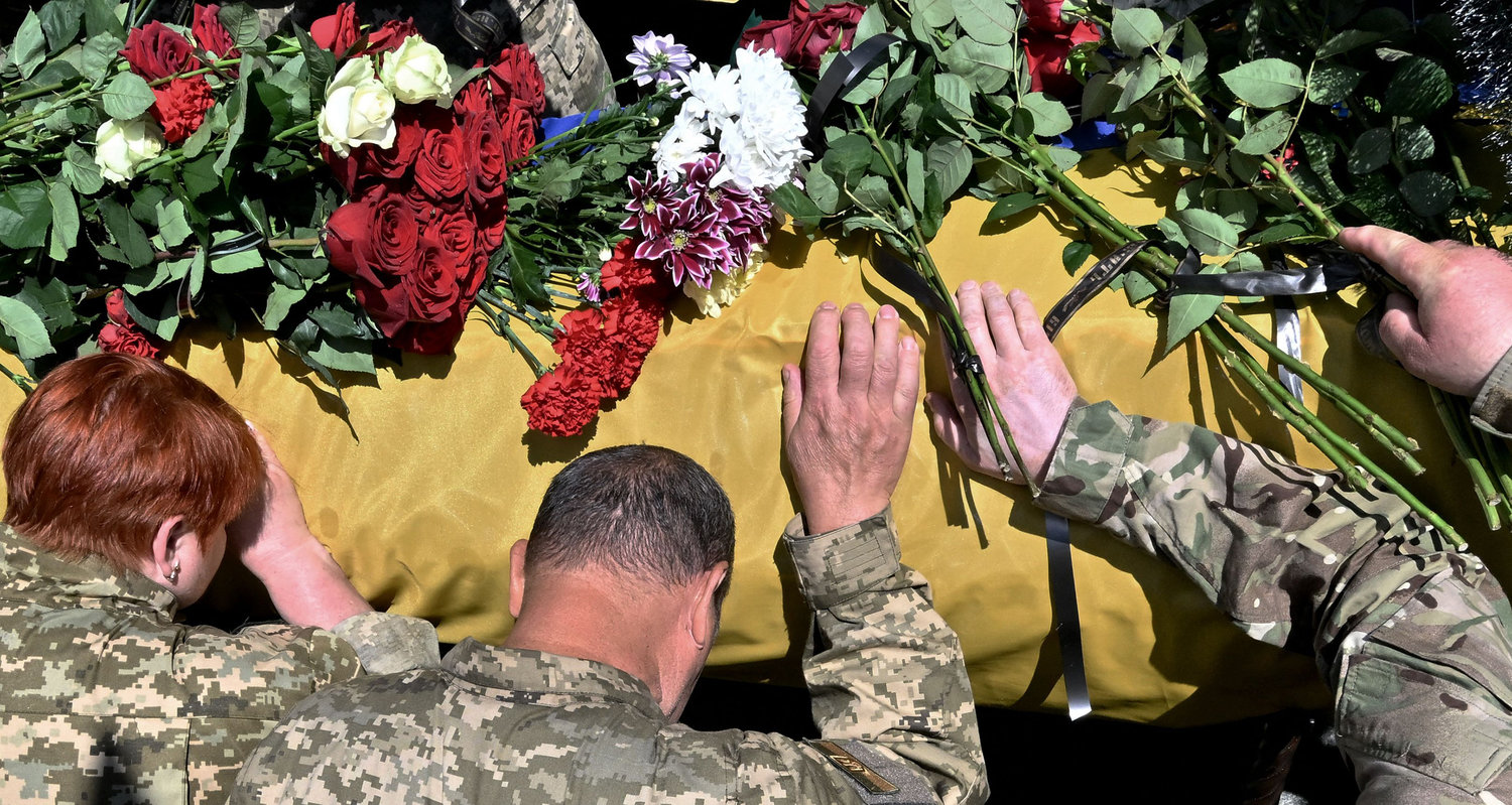 Ukrainian servicemen mourn on the coffin of their comrade Oleh Kutsyn, commander of the "Karpatska Sitch" battalion killed during the war against Russia, during a funeral ceremony at Kyiv's "Maidan" Independence Square on June 22, 2022. (Sergei Supinsky/AFP/Getty Images/TNS)
