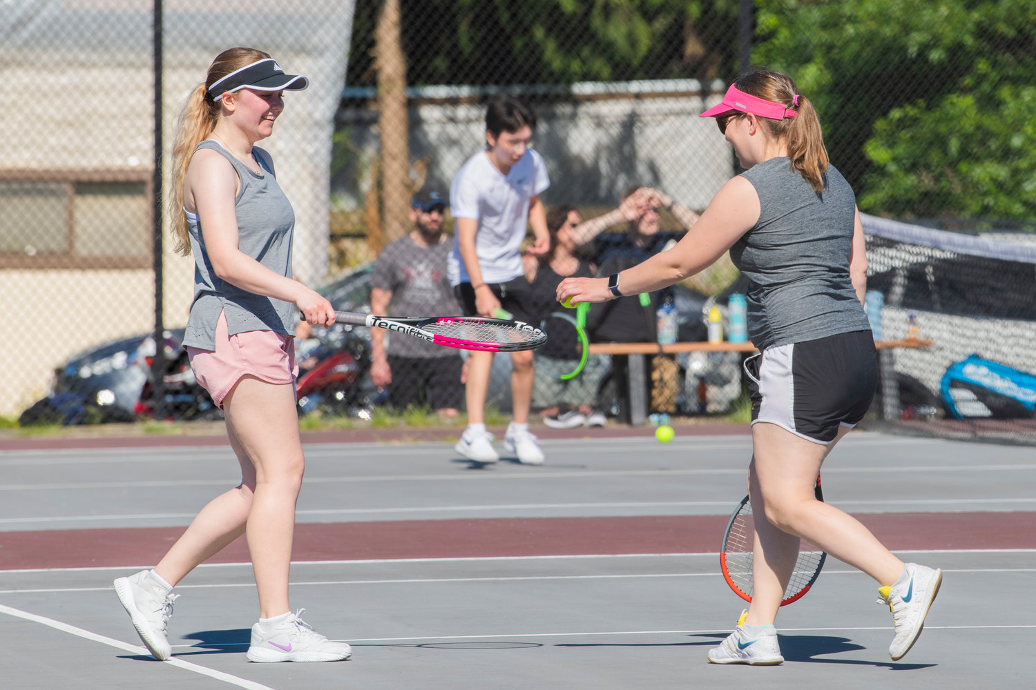 Emma Lund smiles and hands Alex Norris, a Centralia graduate, a ball while playing during the Jack State Tennis Tournament at W.F. West High School on Saturday.