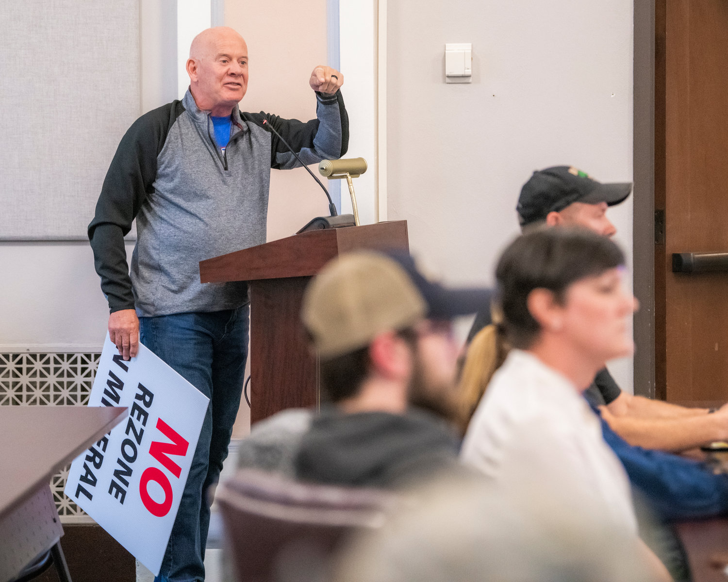 Mike Heinz holds a sign and speaks in opposition of a rezone at Mineral Lake during a public hearing held by the Lewis County Planning Commission in Chehalis on Tuesday.