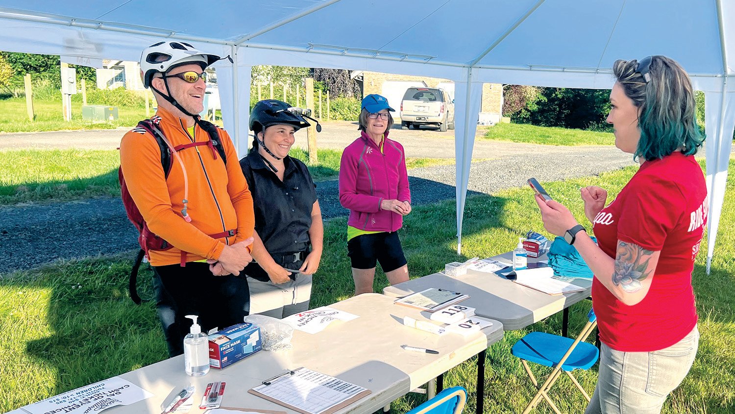 Riders and staff exchange a smile at the Ride the Willapa check-in tent at Owl & Olive near Pe Ell.