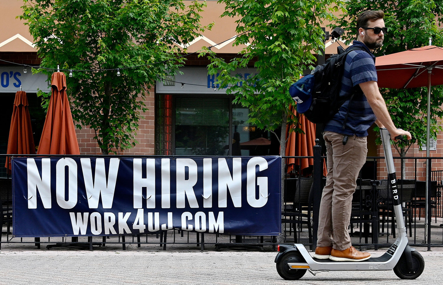 A man riding a scooter passes in front of a "now hiring" sign posted outside of a restaurant in Arlington, Virginia on June 3, 2022. (Olivier Douliery/AFP via Getty Images/TNS)