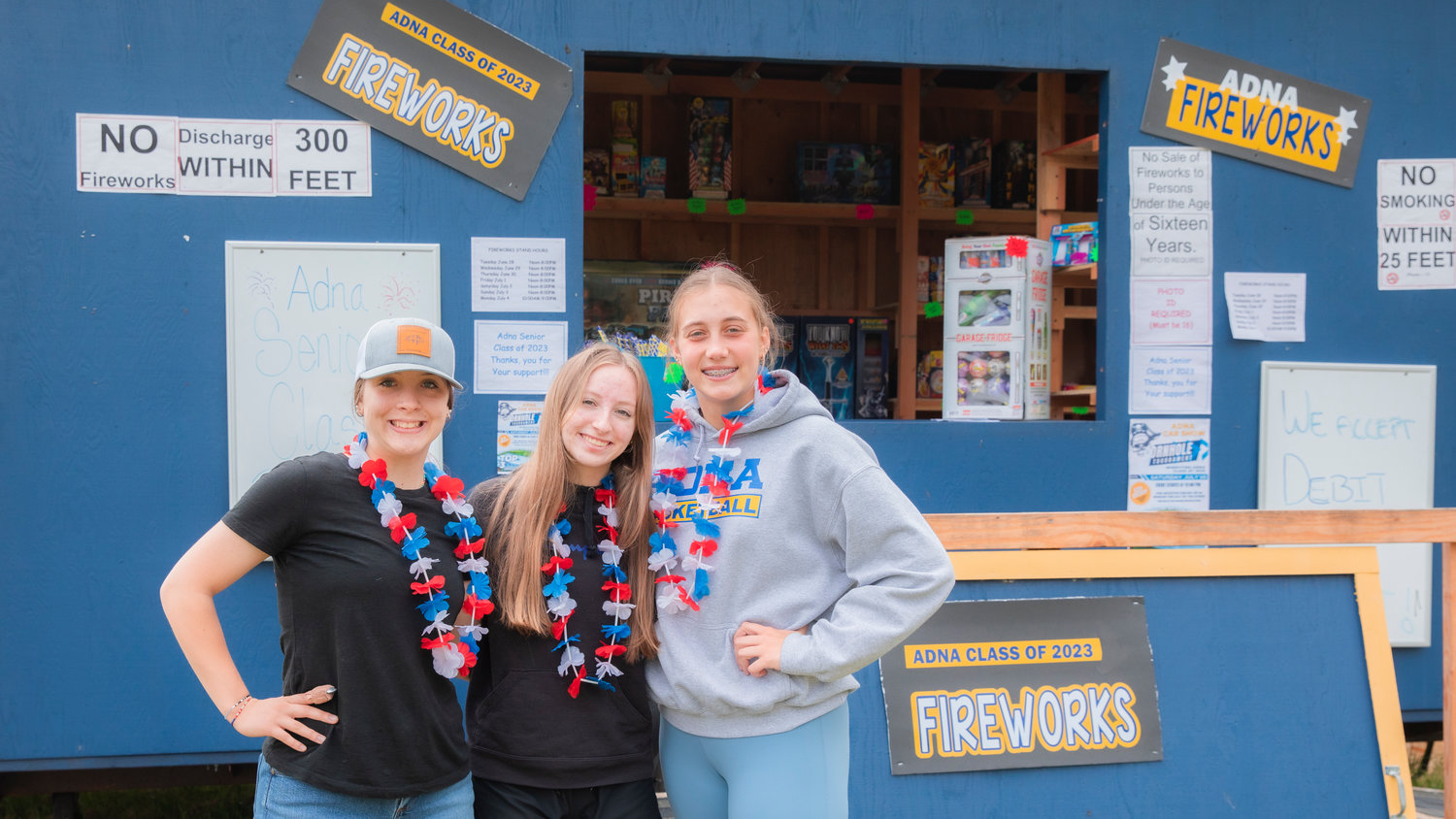 From left, Abby McAuley, Annie Murphy and Karlee VonMoos smile for a photo while selling fireworks and helping to raise money for the 2023 senior class at Adna High School Friday afternoon.