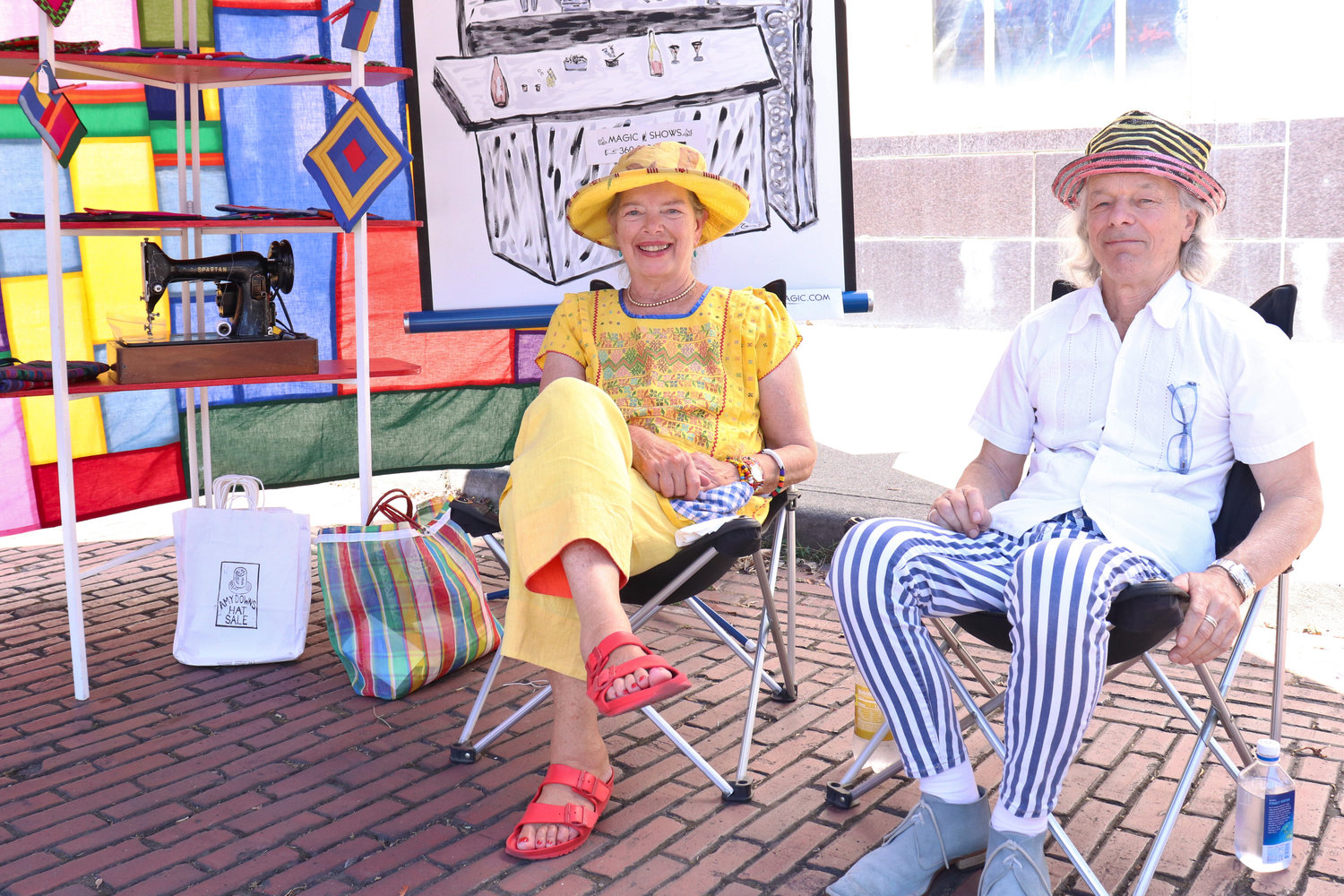 Hatmaker Amy Downs and magician G. Sparks cool off in the shade of their joint tent, Hat Magic, at Antique Fest in downtown Centralia on Sunday.