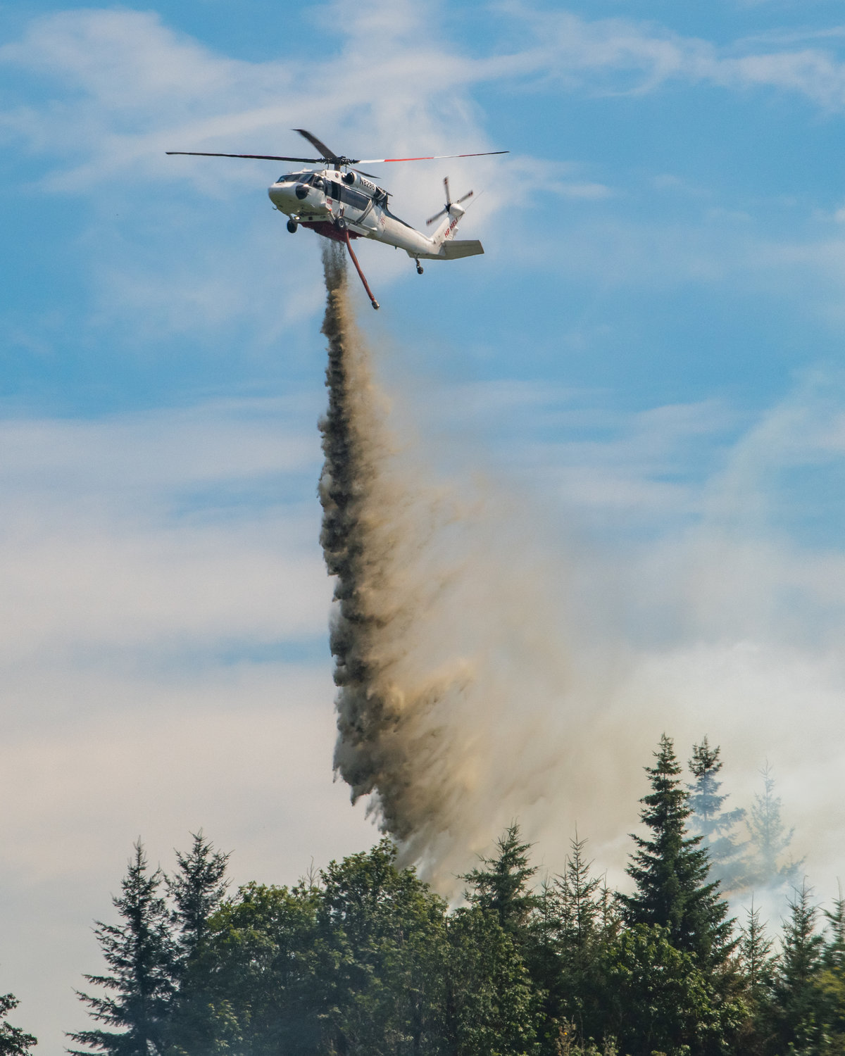 A Department of Natural Resources helicopter flies over Bucoda Monday afternoon while dumping water from the Skookumchuck River on a forest fire near the intersection of Highway 507 and Troy Avenue.