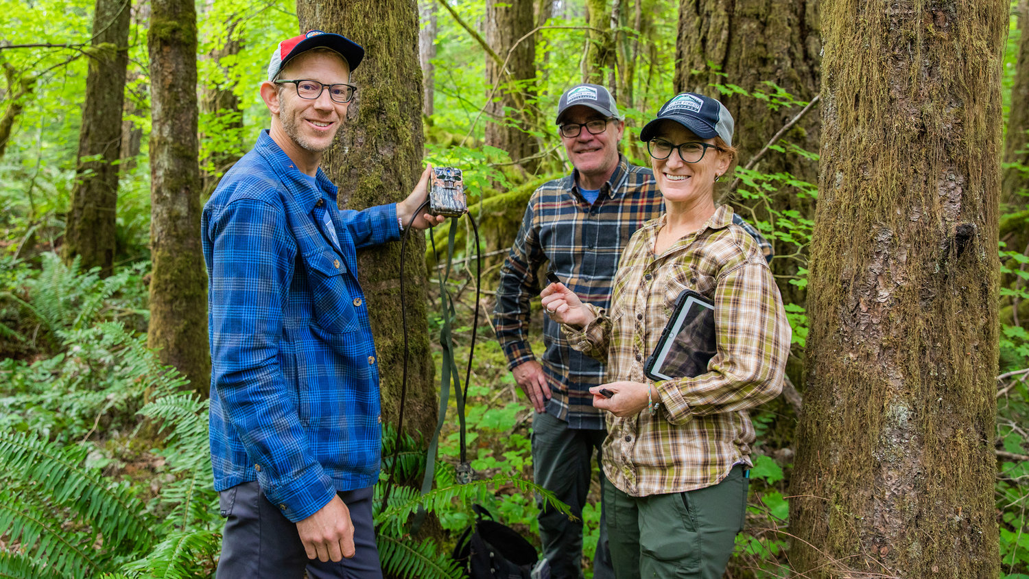 From left, Brian Yellin, Jeff Green and Kim Freeman, all of Portland, smile for a photo with a game camera retrieved from the Gifford Pinchot National Forest in Lewis County Saturday morning.