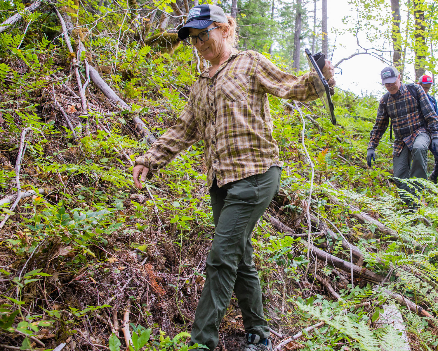 Kim Freeman smiles while searching for a game camera alongside Jeff Green and Brian Yellin Saturday morning in the Gifford Pinchot National Forest in Lewis County.
