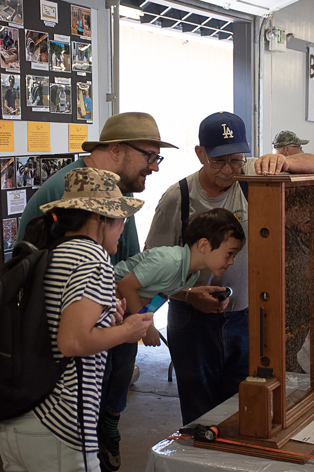 Bret Bryan (LA hat), a beekeeper and member of the Lewis County Beekeepers Association, helps fair-goers local the queen in the live beehive exhibit at their stand. Photo by Owen Sexton.