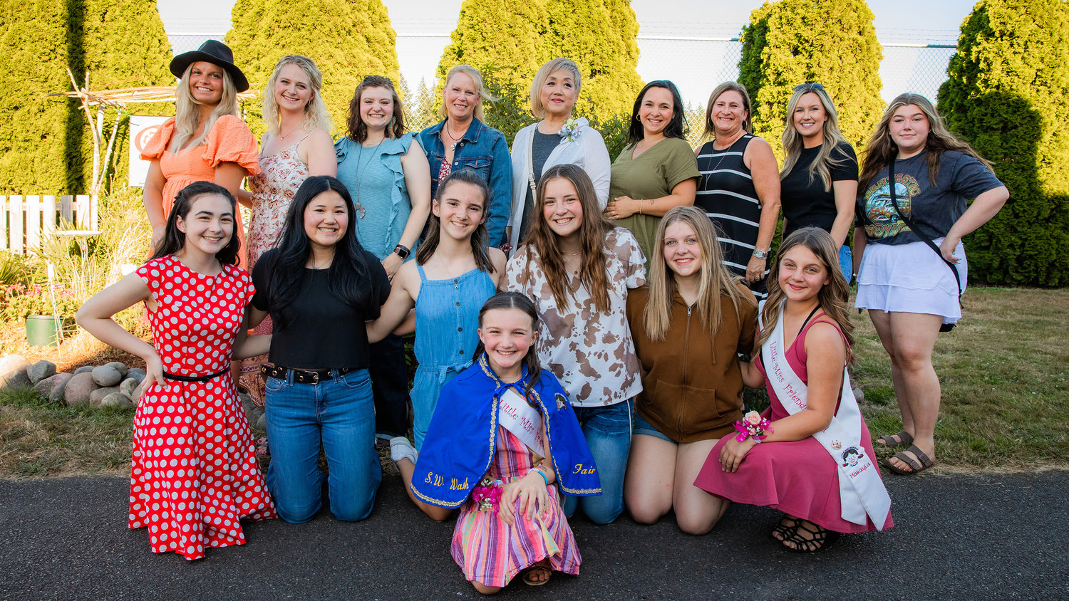 Emma Britton smiles for a photo with Little Miss Friendly alumni after donning the cape on the Saloon Stage at the Southwest Washington Fairgrounds on Tuesday. Back row left to right, Shasta Lofgren 2007, Bailey Peters Moon 2006, Camille Curfman 2005, Kathy Morrison 1973, Nani Jackins 1975, Rachel Gillispie 1993, Julie Briggs Moore 1979, Cassidy Best 2003, Aubrie Morey 2014. Second row left to right, Haiden Bartel 2019-20, Campbell Senter 2016, Natalie Butler 2018, Rachel Gray 2015, Reese Coleman 2017 and MaKayla Maynard 2021.