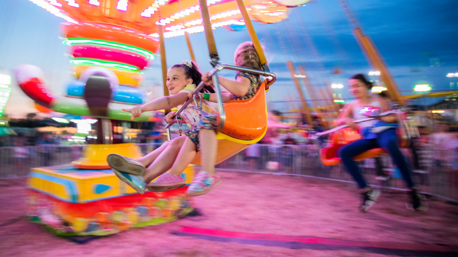 Violet Rogers, 9, of Boistfort, points on while spinning on a ride at the Southwest Washington Fairgrounds in August 2022.