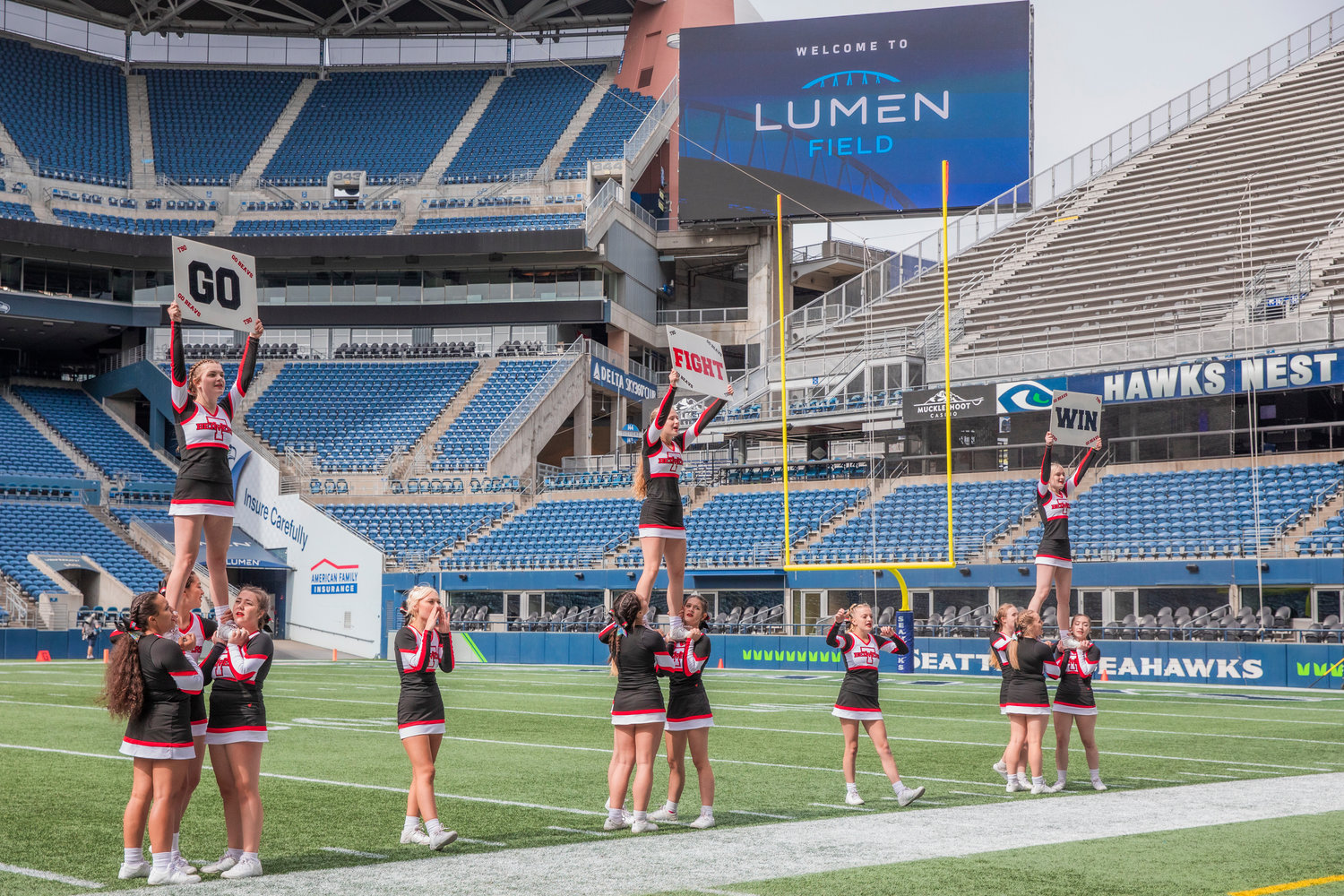 Tenino cheerleaders hold signs and chant Saturday afternoon at Lumen Field in Seattle.