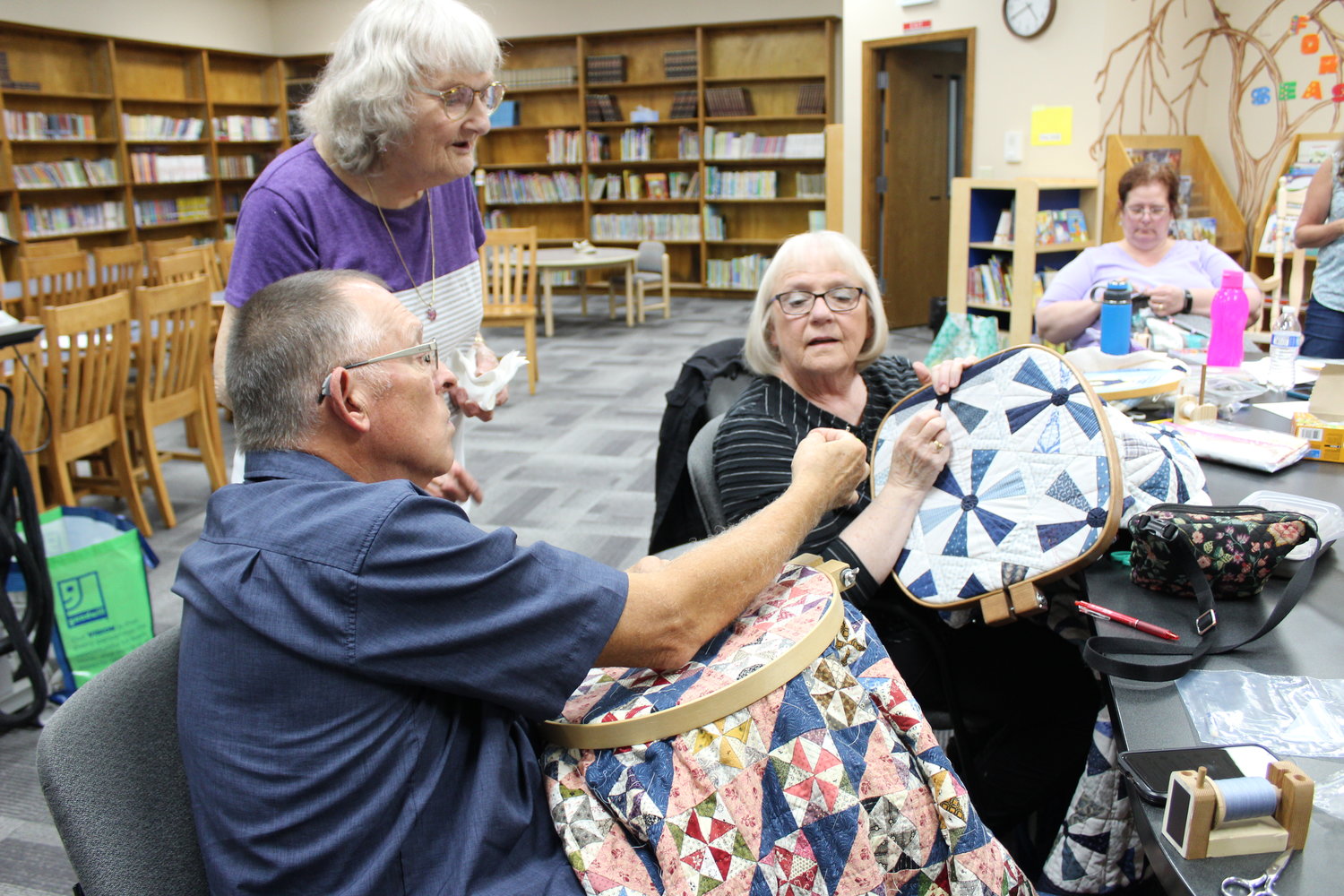 Rick Sundstrom shows an incredibly small quilting needle to Judy Cobd and Susy Carpenter during a meetup of the In Stitches quilting group, which will hold its final public show Sept. 30 and Oct. 1 at Centralia Christian School.