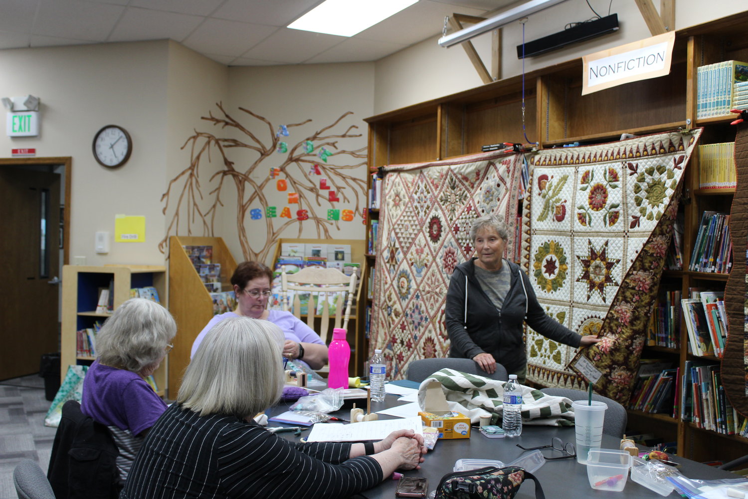In Stitches quilt group member Geralyn Reed shows one of her completed projects to the group during one of their meetups. Members celebrate each completed piece by singing "Happy Quilting to You" sung to the tune of the birthday song and by enjoying homemade treats.