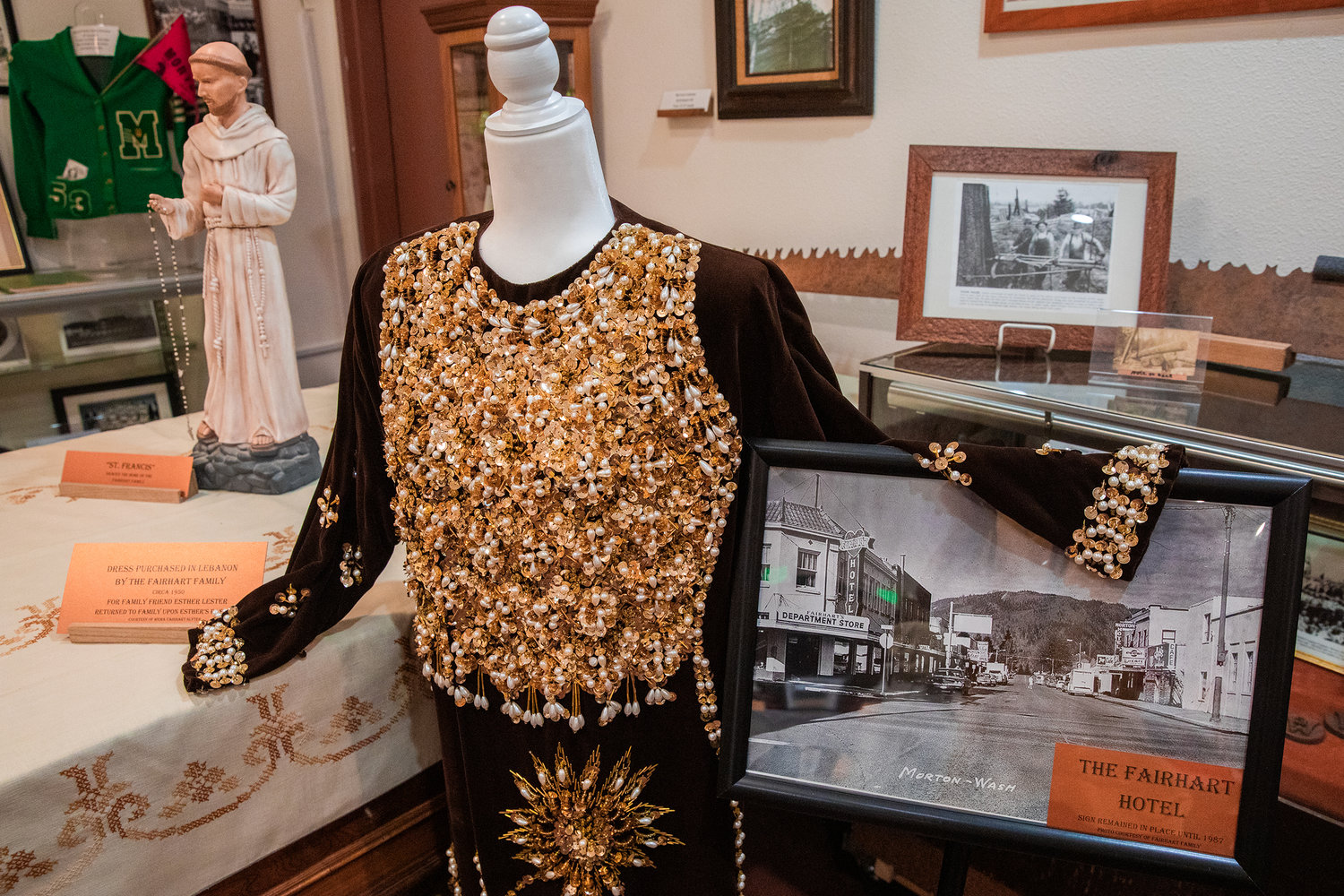 A dress made by members of the Fairhart family sits on display next to a photo showing the Fairhart Store in downtown Morton where signage remained until 1987.