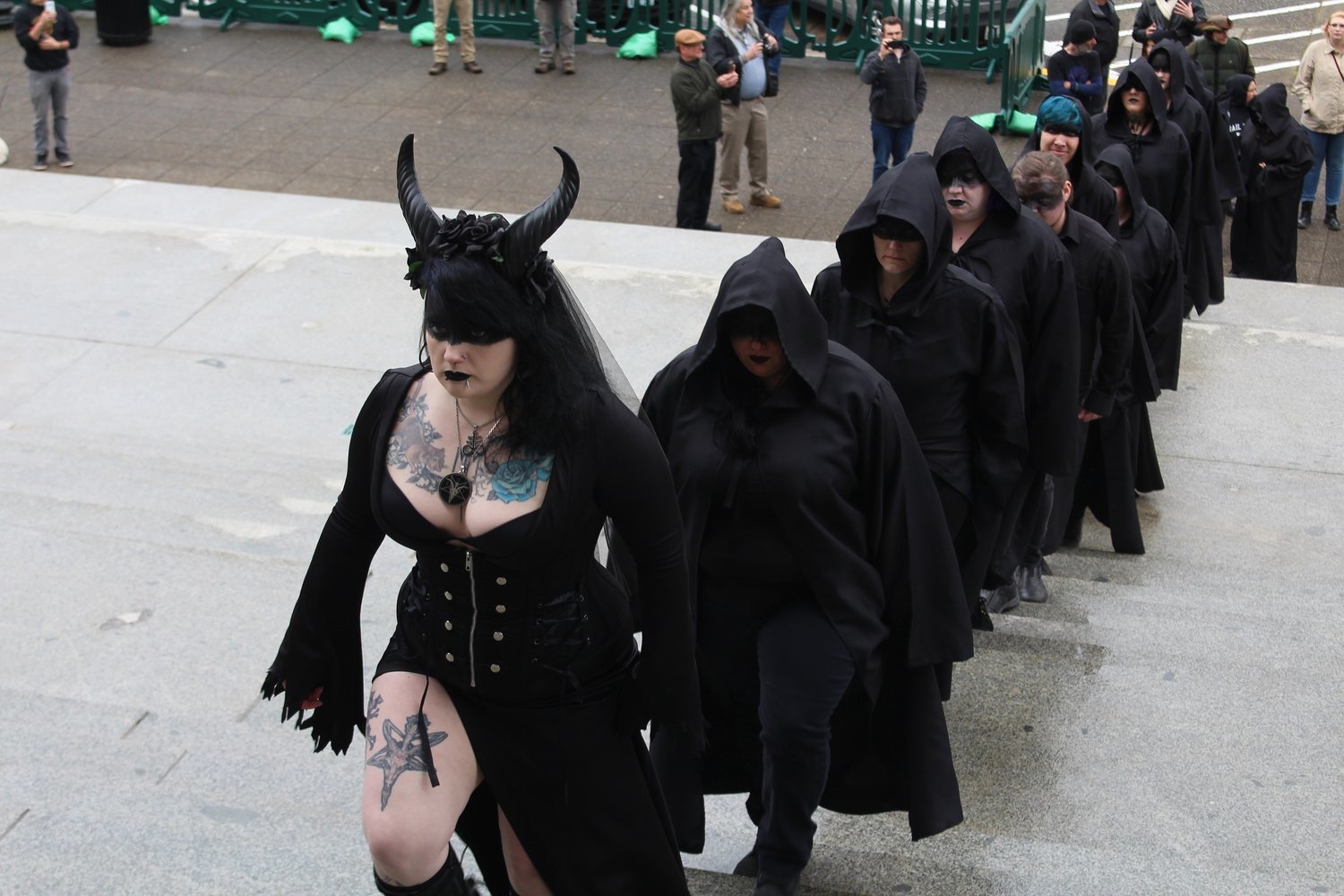 Angel, who goes by one name and is the ritual guild leader for the Satanic Temple of Washington State, leads a procession up the Washington Capitol steps as part of their ritual in this 2019 WNPA News Service file photo.