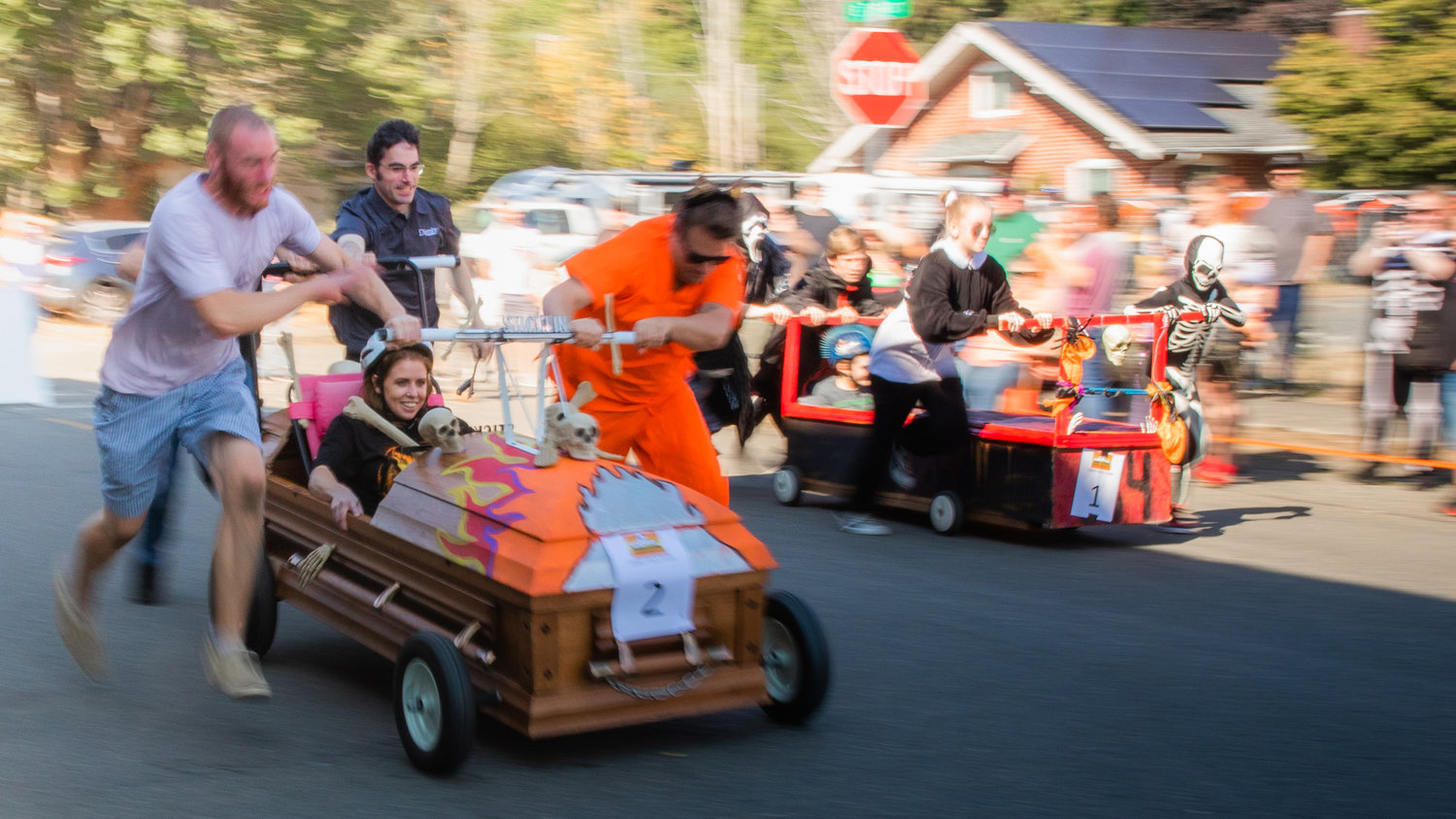 Teams race down East 7th Street during the Boo-coda Casket Races on Saturday.