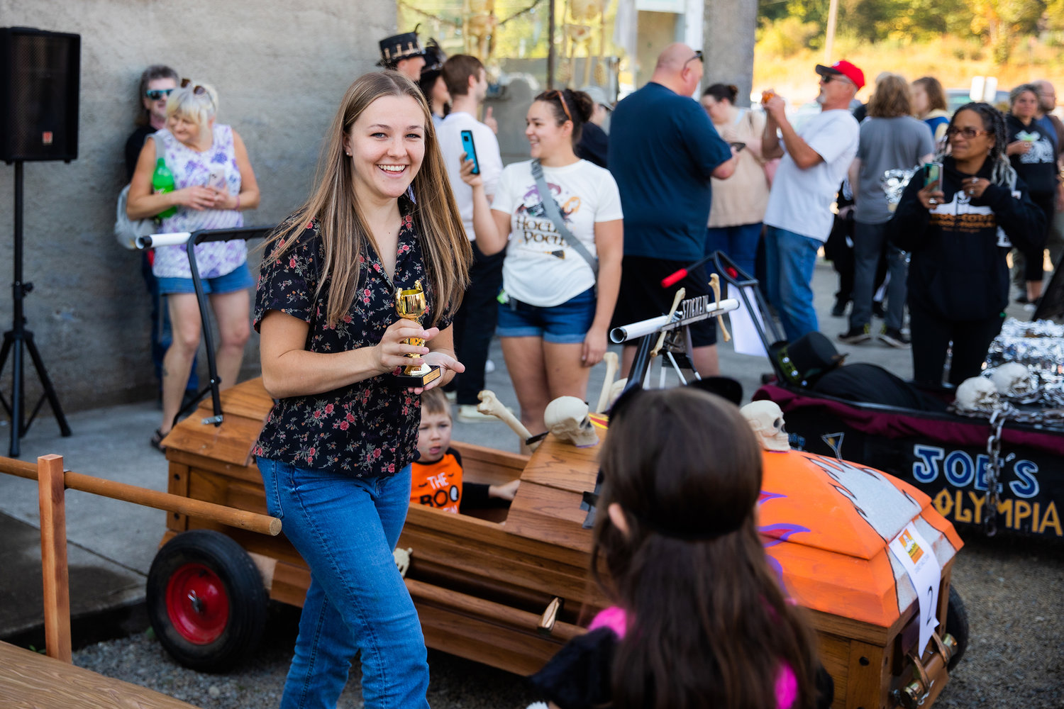 Reporter Isabel Vander Stoep smiles while collecting a third place trophy for the “DEADline News,” team during the Boo-coda Casket Races on Saturday.