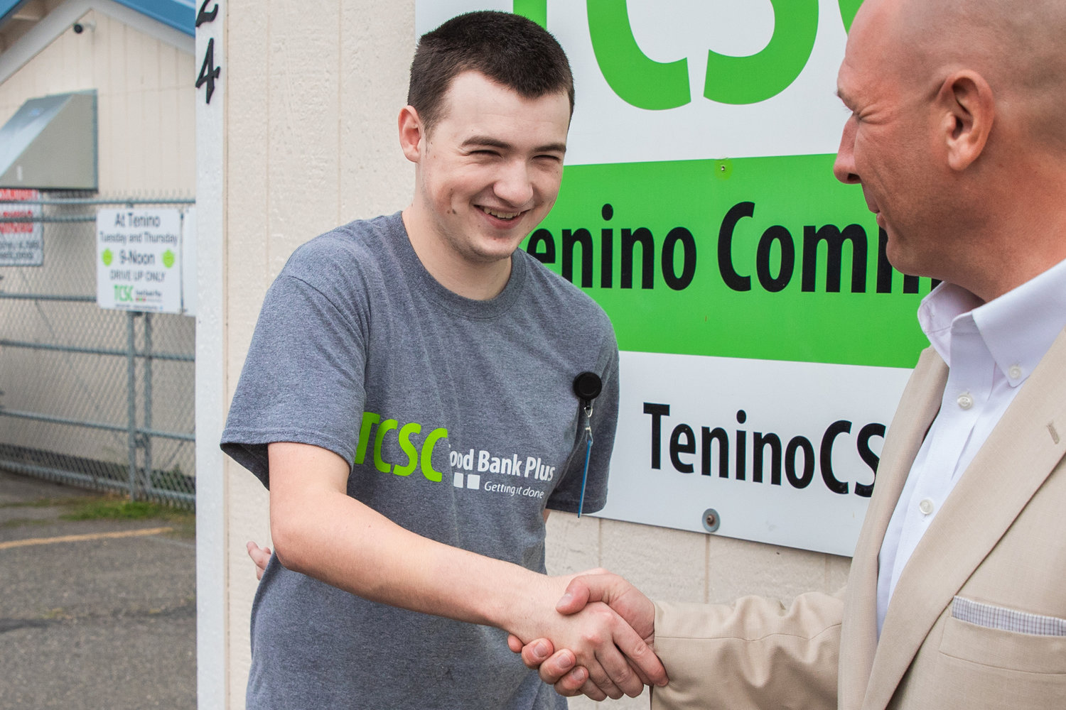 State Rep. Peter Abbarno smiles while shaking the hand of Korbin Pearson, 21, a Tenino graduate with special needs who works at the location three days a week as part of a newly established program at Tenino Food Bank Plus.