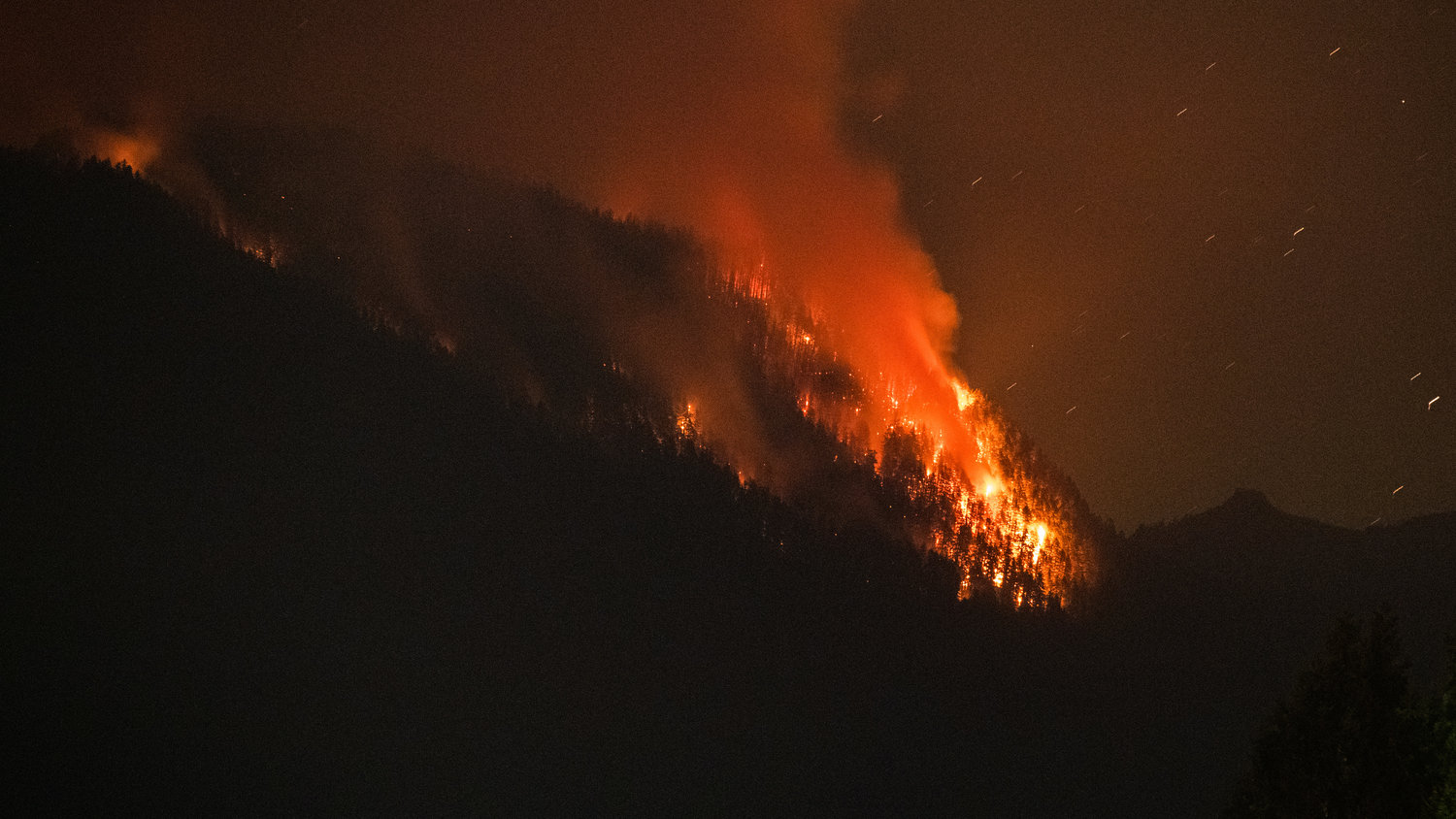 Flames from the Goat Rocks Fire ignite trees earlier this month as seen from Cannon Road in Packwood over Butler Creek.