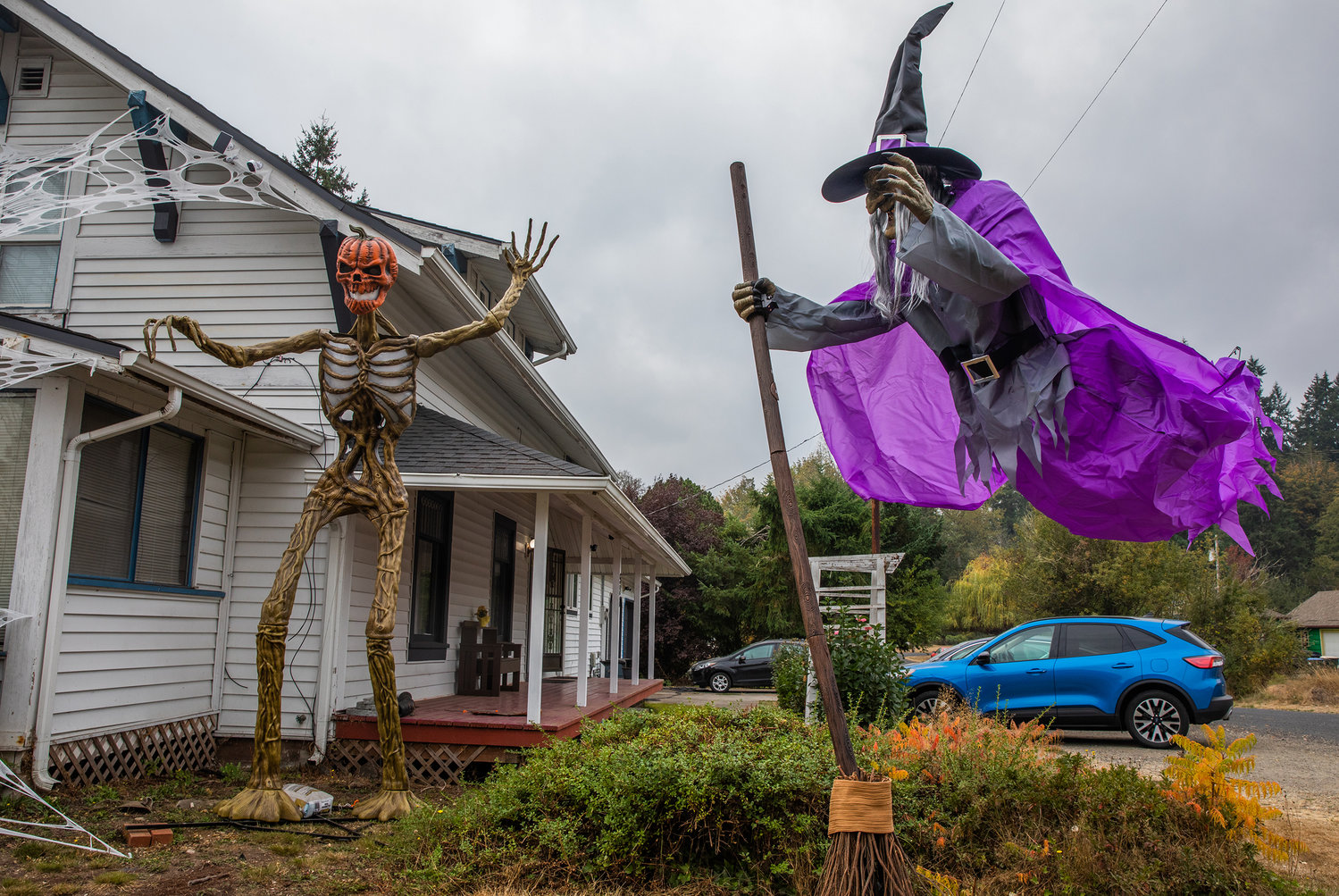 A witch with a broom and a skeleton with a pumpkin head guard the intersection of state Route 505 and Hemlock in Toledo on Thursday.